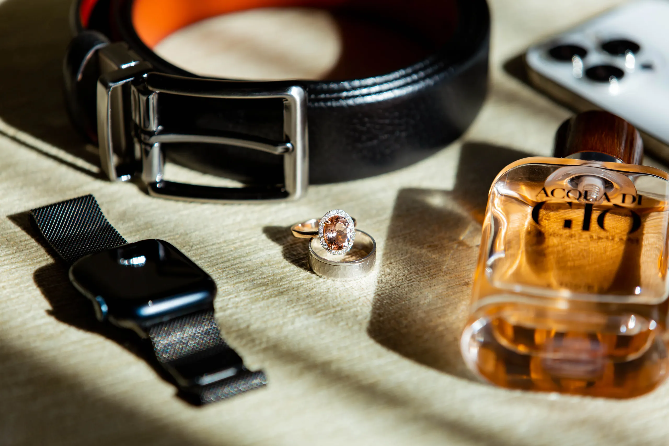 Belt, smartwatch, ring and cologne in morning light