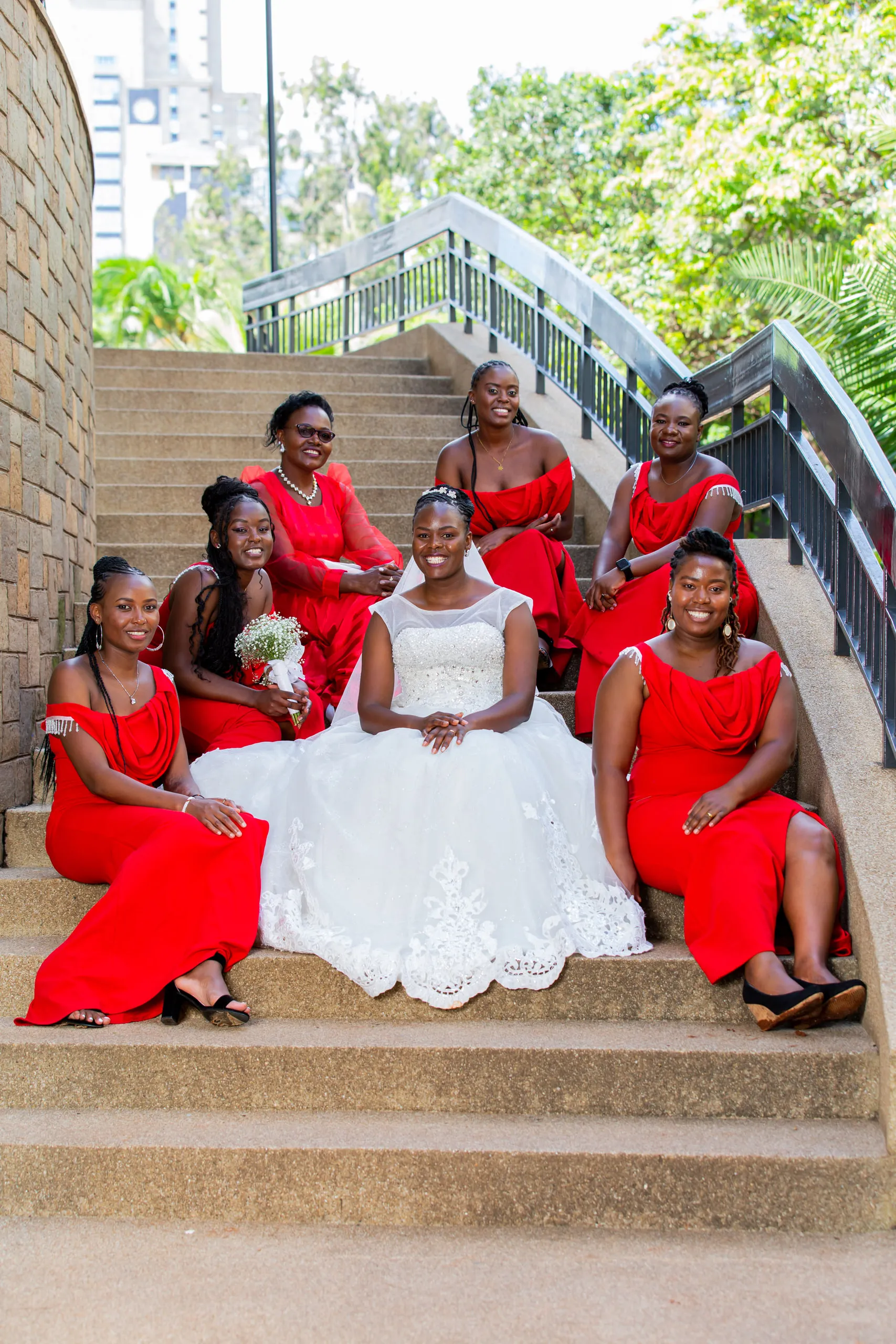 Bride and bridesmaids in red sitting on outdoor steps