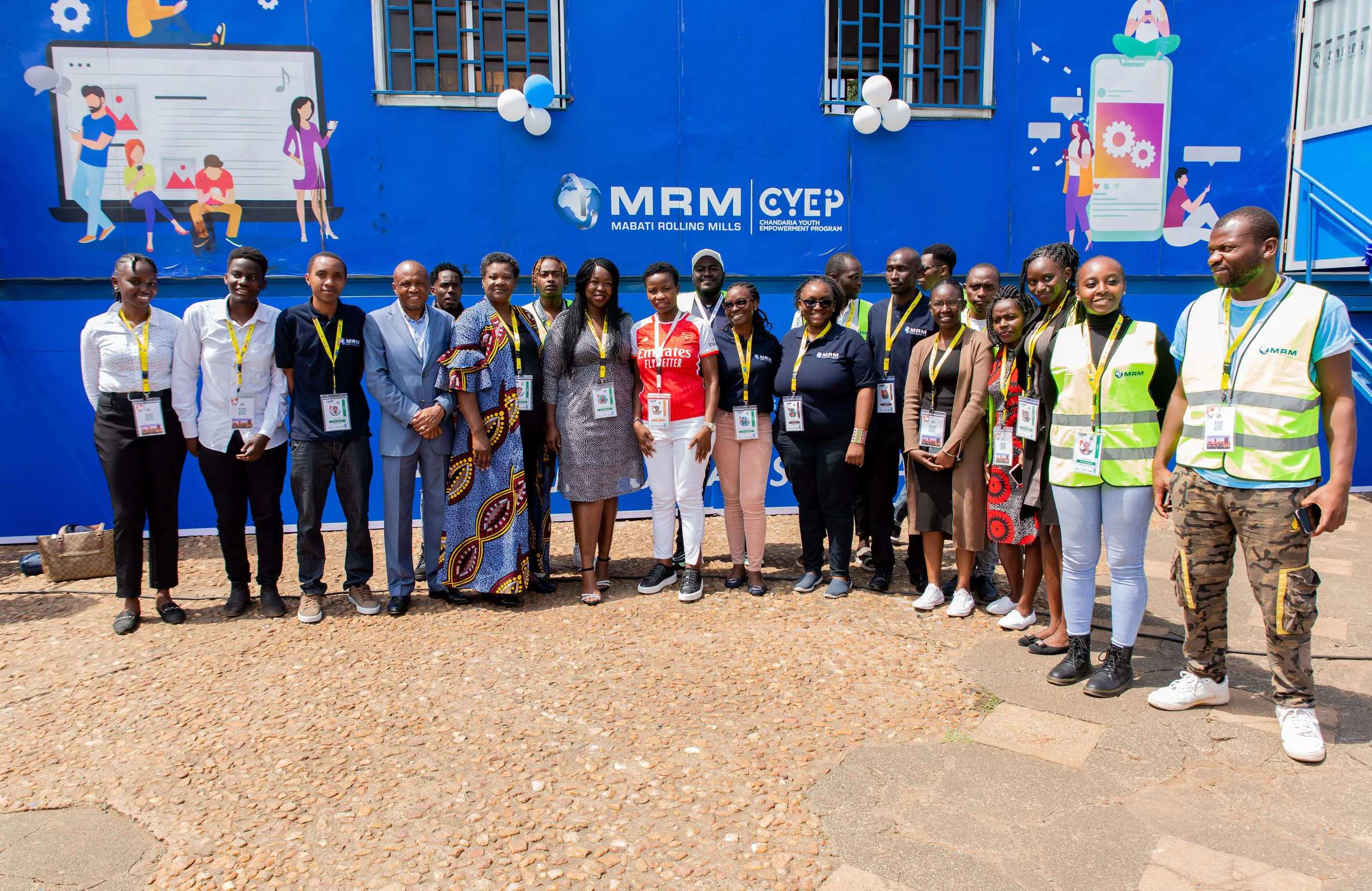 Group of staff and guests with lanyards posing in front of a blue branded container