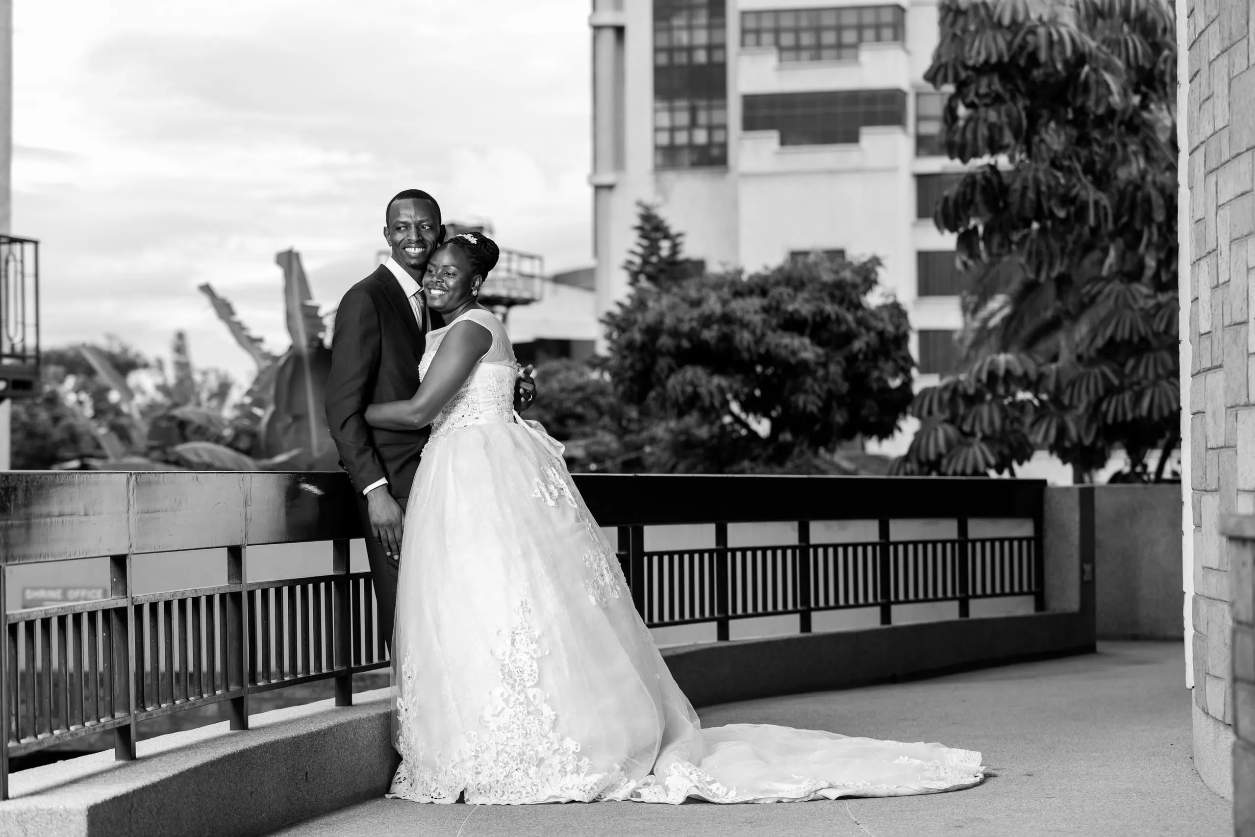 Bride and groom embracing on a balcony above the city, in black and white