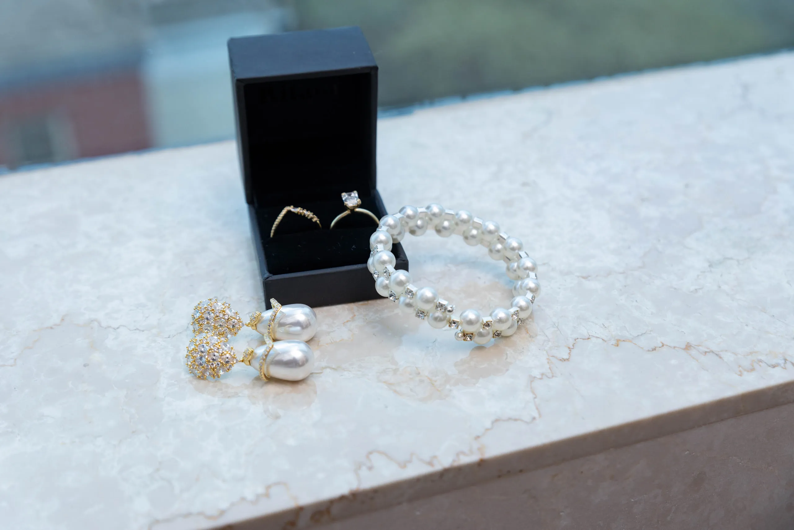 Wedding rings in a black box with pearl earrings and a bracelet