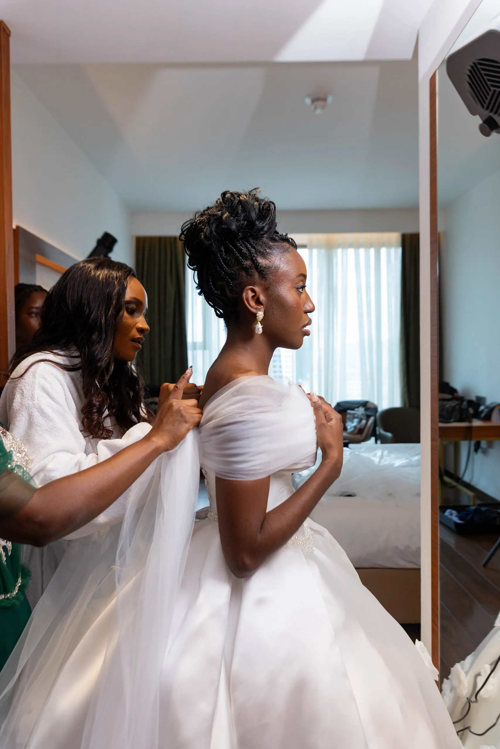 Bride in profile while her tulle sleeves are adjusted