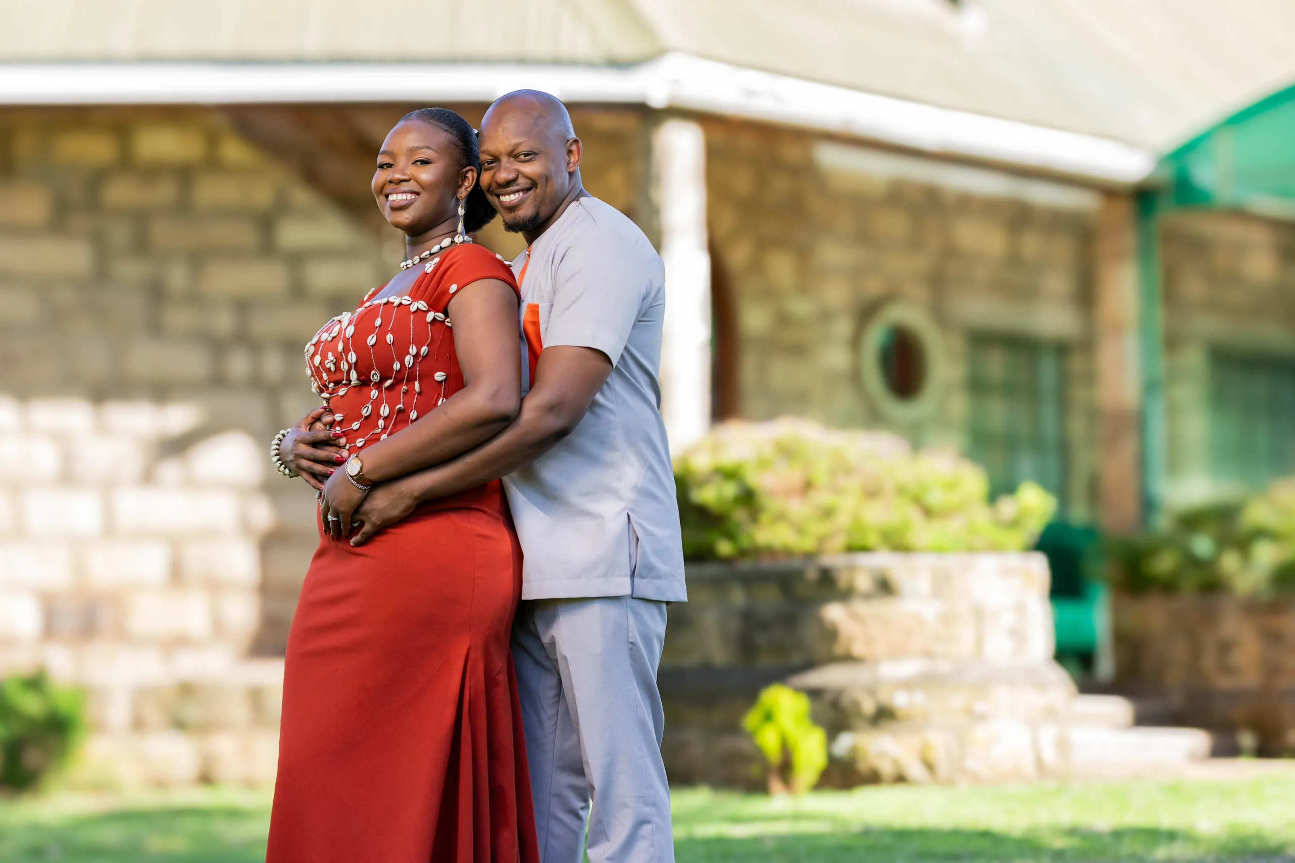 Couple in red and white traditional dress outside a homestead
