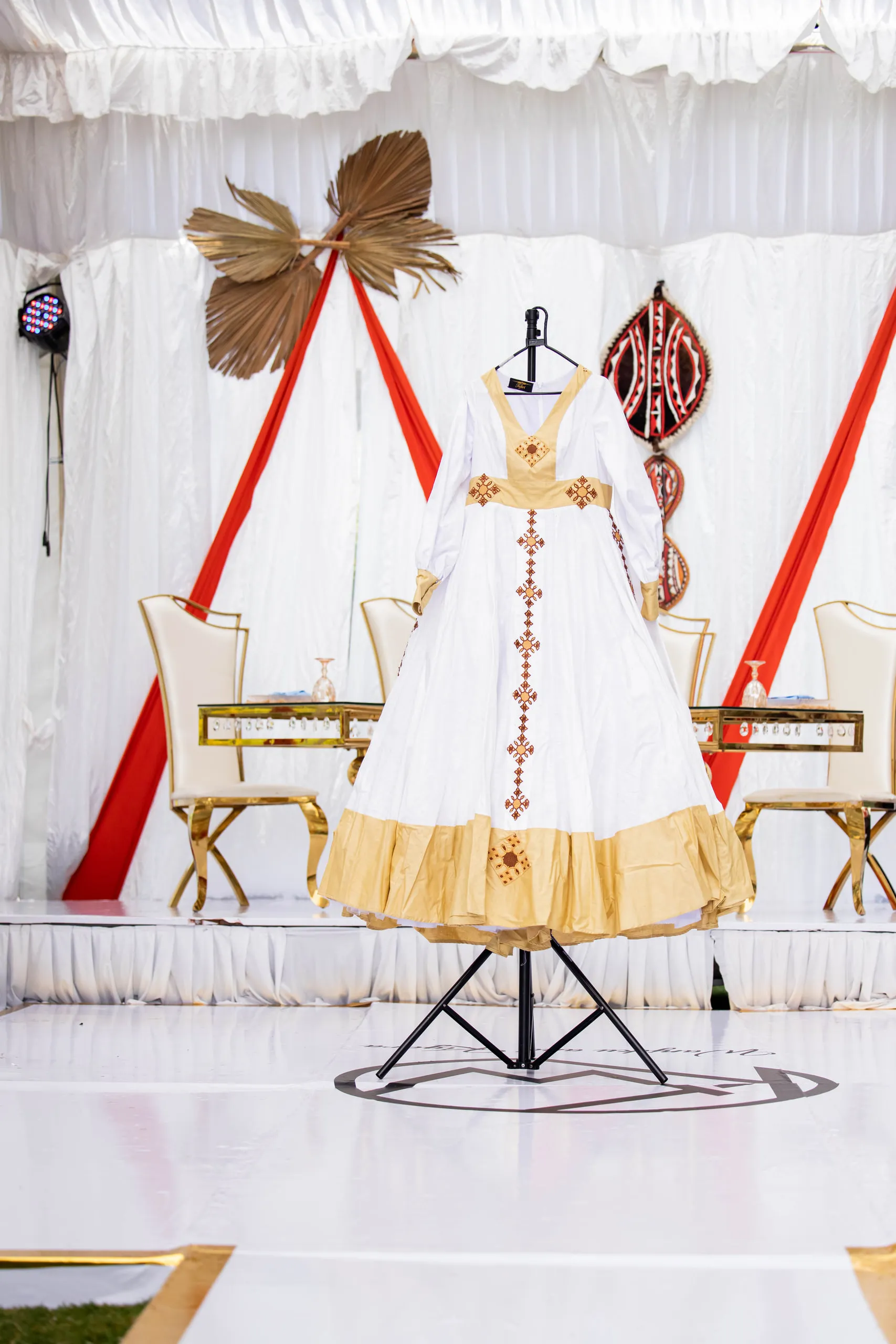 White and gold traditional gown on a stand before a decorated stage