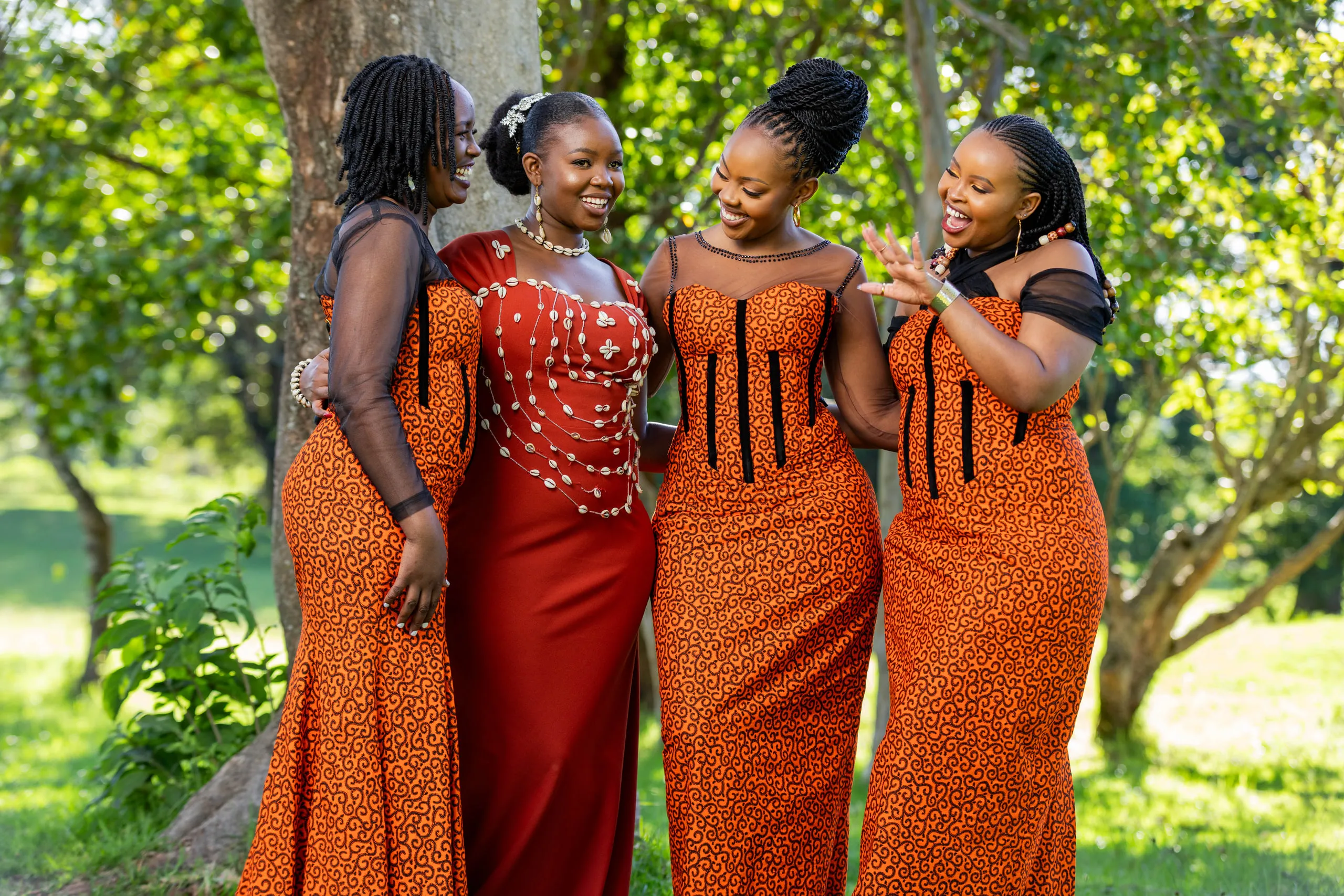 Bride laughing with three women in orange print dresses