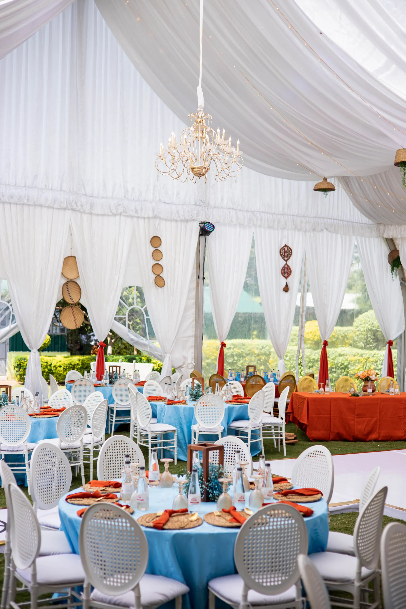 Tent with a chandelier and blue and orange tables