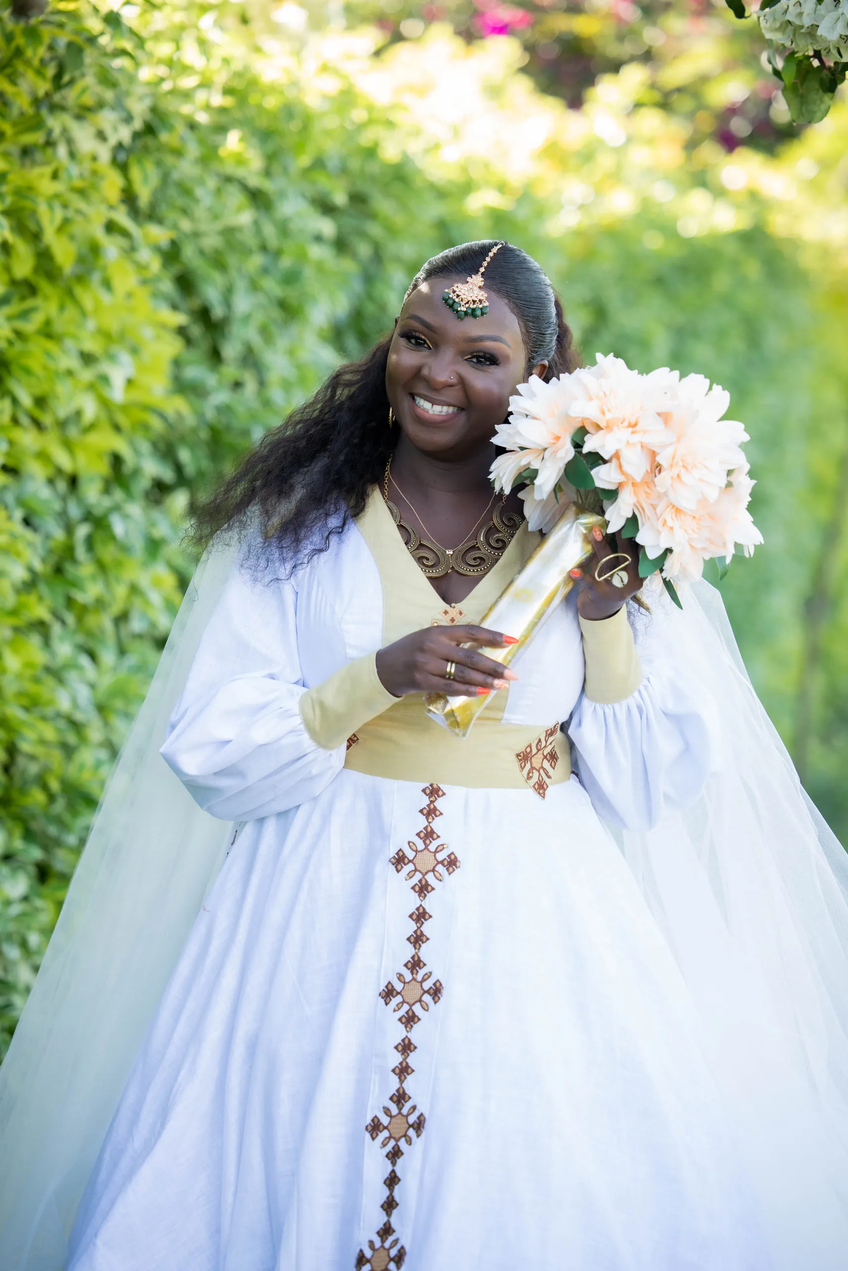 Bride in a white and gold embroidered dress with a bouquet and a head chain