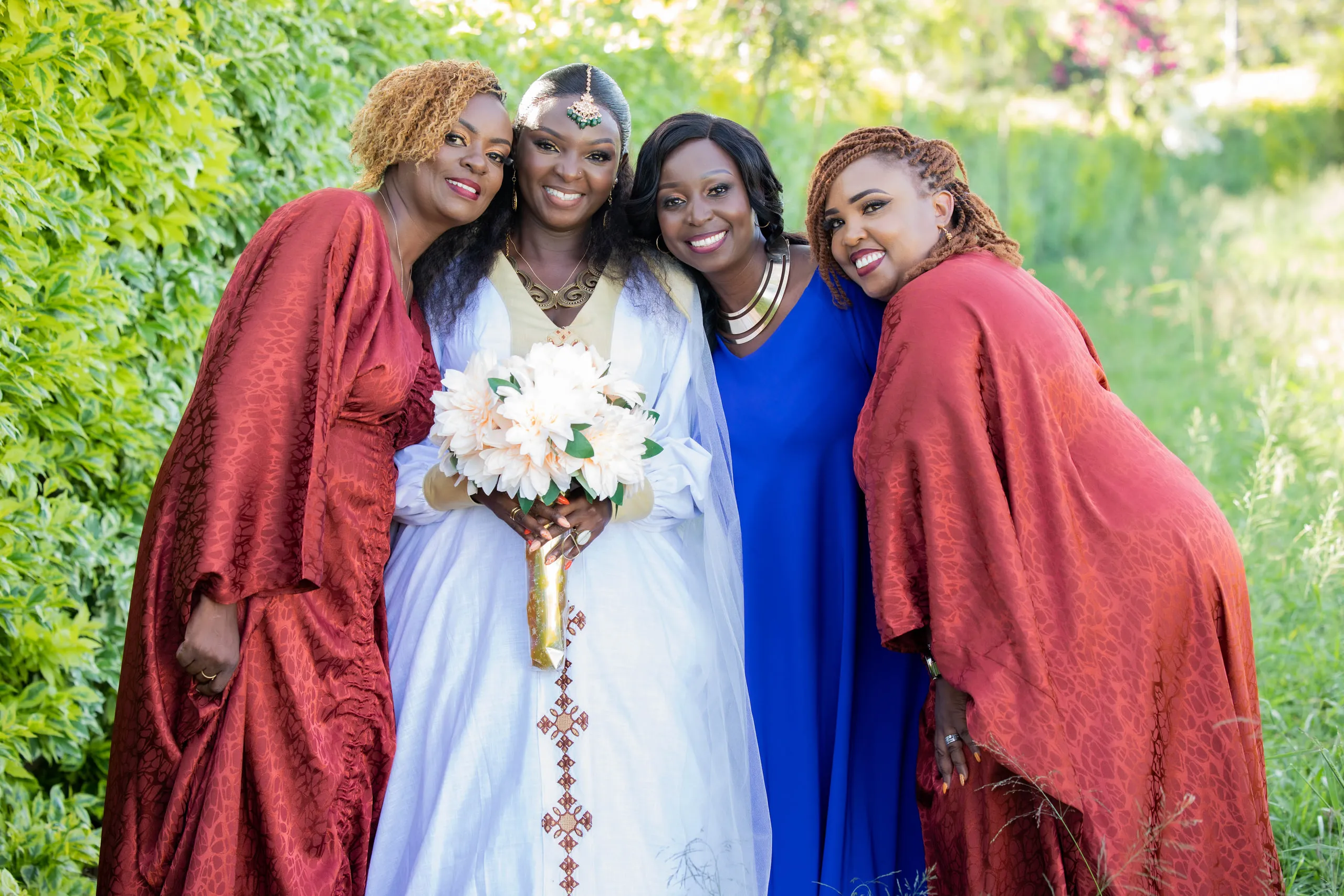 Bride with her family in red shukas, holding her bouquet