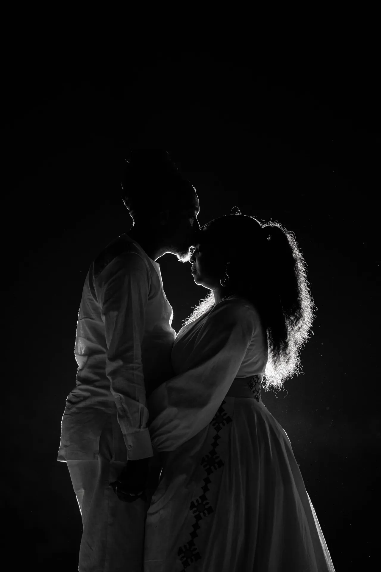 Silhouette of a couple about to kiss, lit from behind