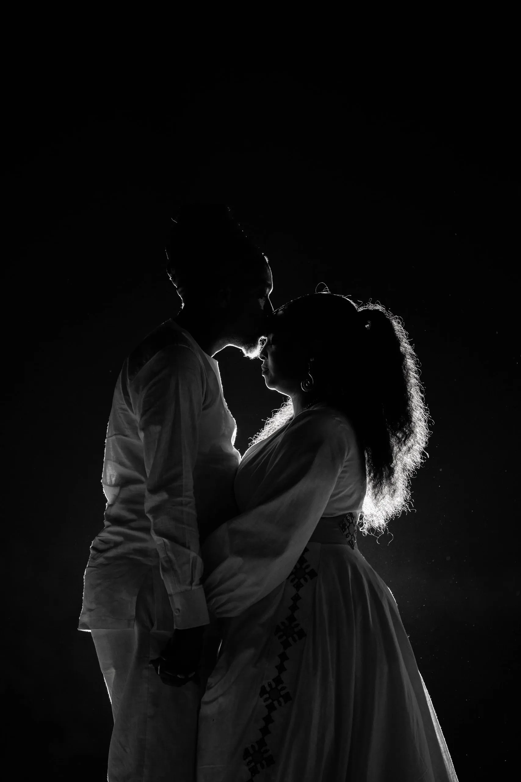 Silhouette of a couple about to kiss, lit from behind