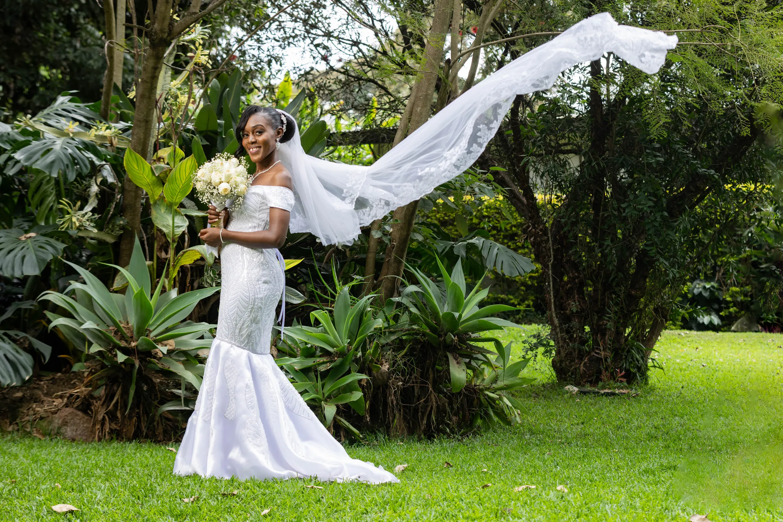 The wind lifting the bride's veil on a garden lawn