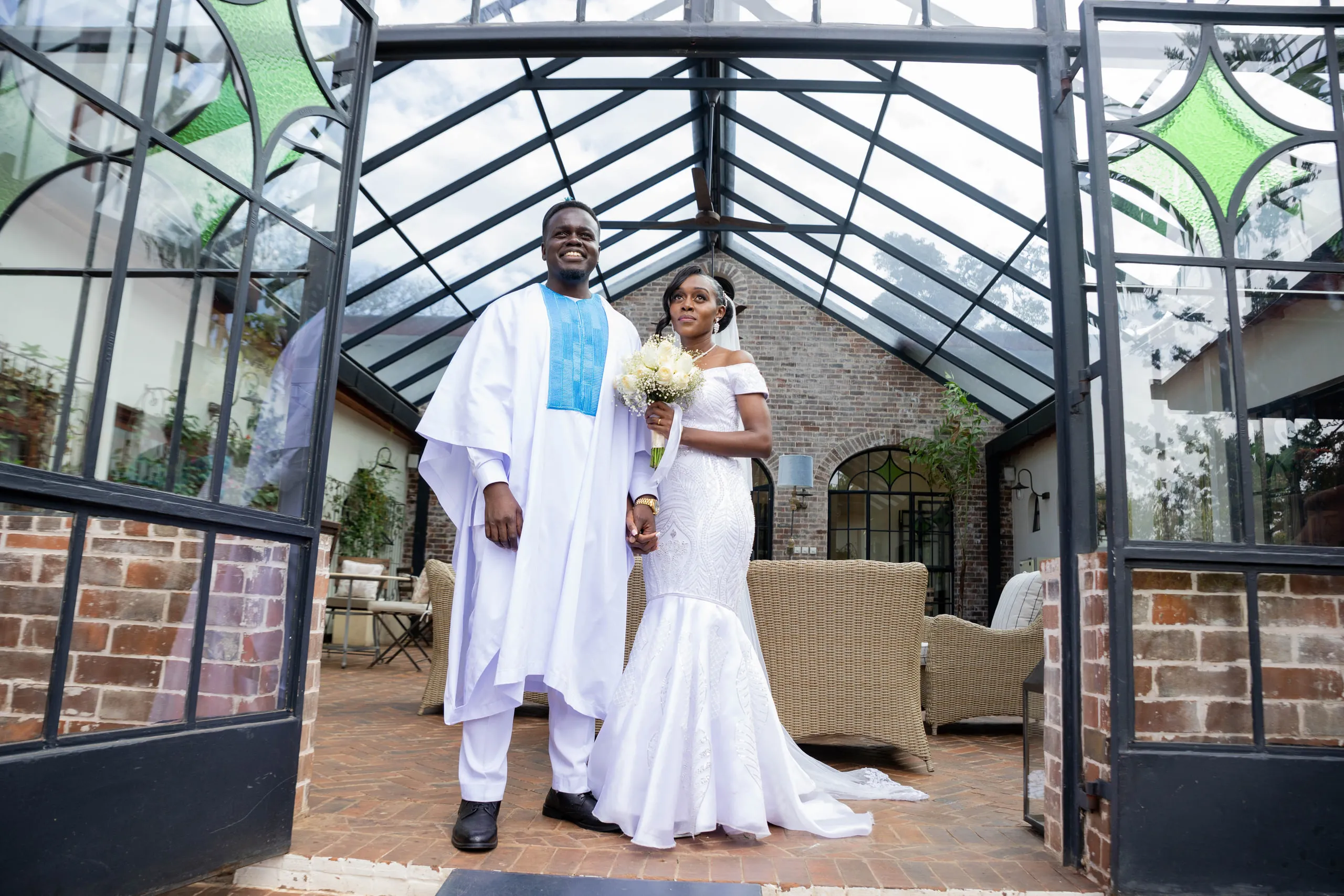 Bride and groom standing together inside a glasshouse