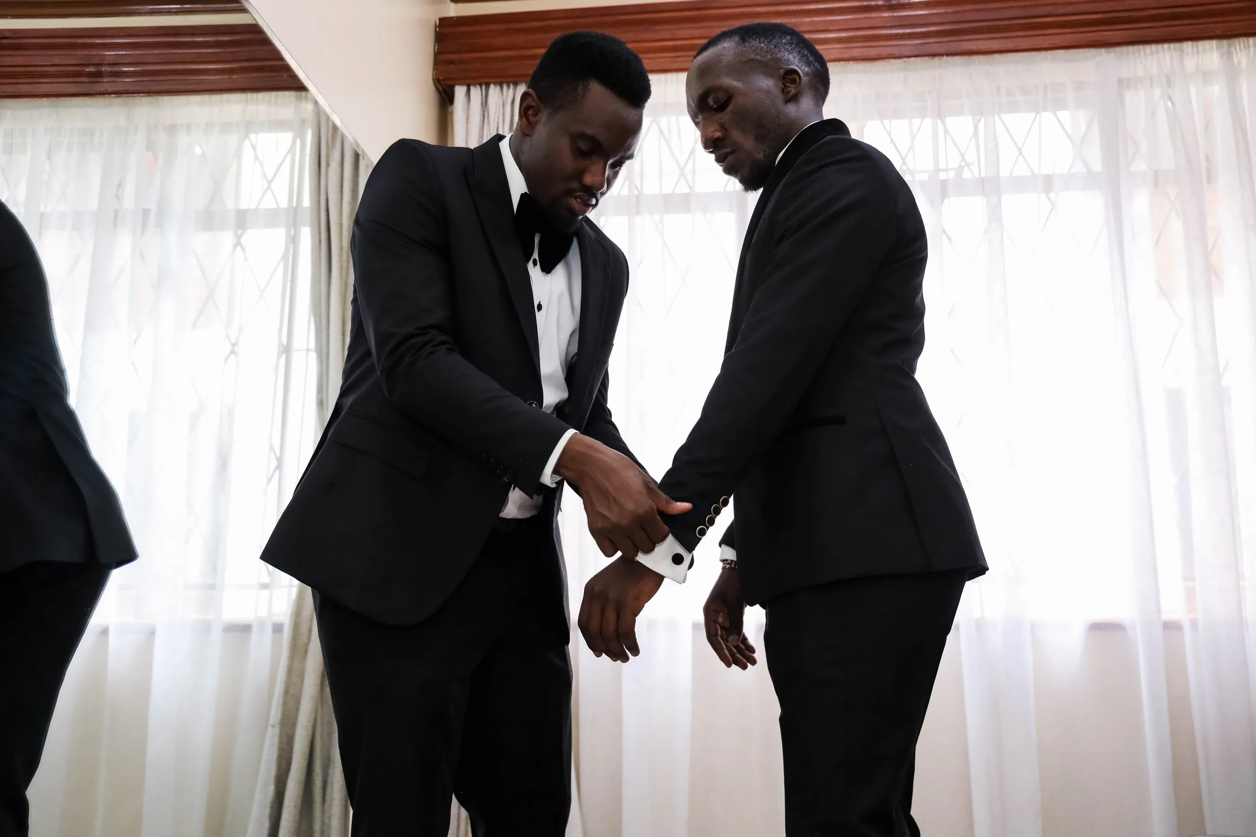 Groom and his best man fastening a cufflink