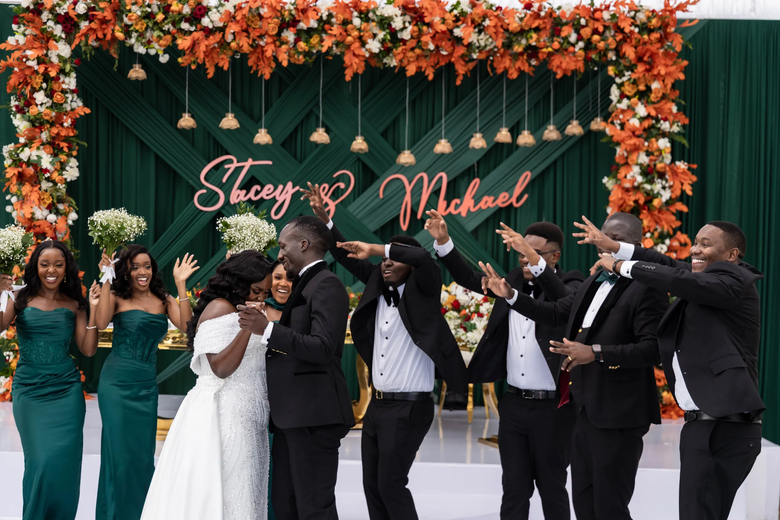 The wedding party celebrating in front of a floral backdrop