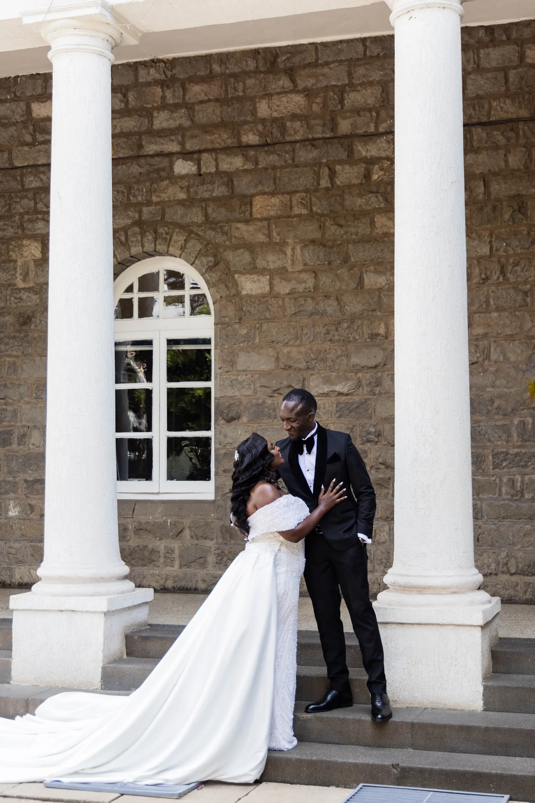 Bride and groom kissing between white columns on stone steps