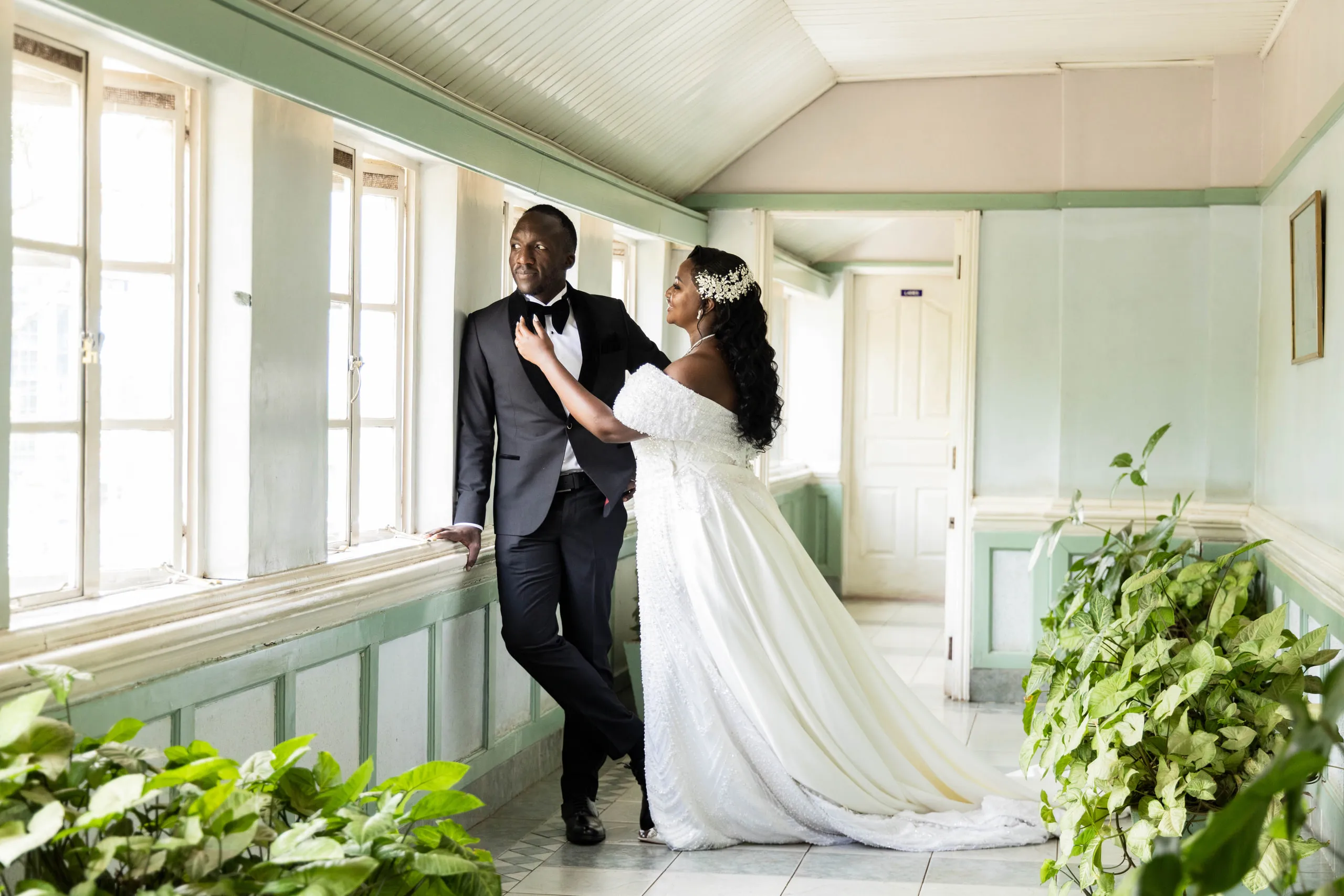 Bride and groom in a long green corridor with plants along the wall