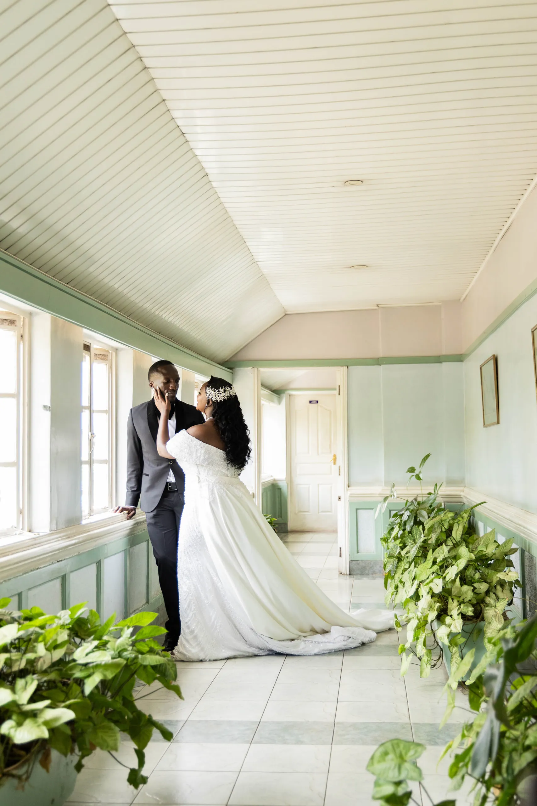 Bride and groom by a window at the end of a green corridor