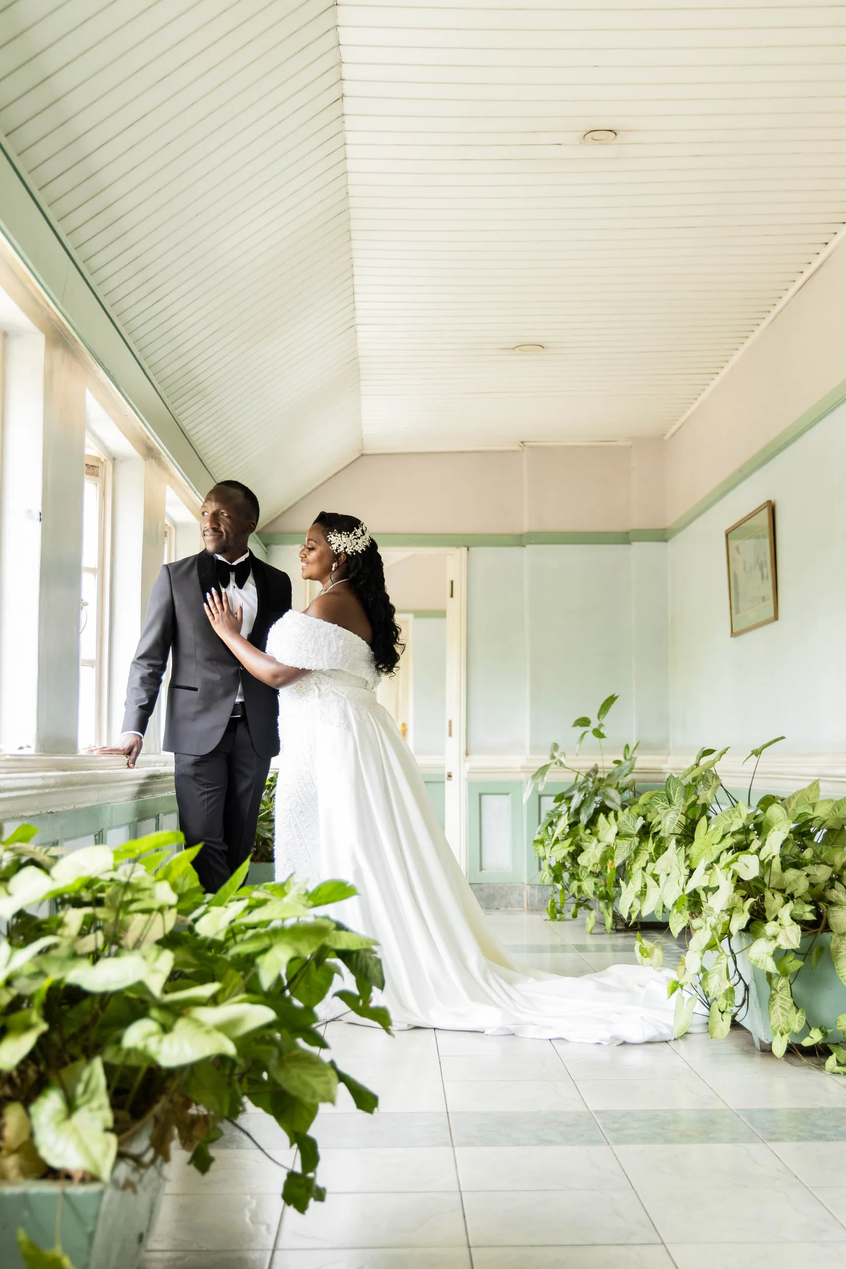 Bride and groom in a long green corridor lined with plants