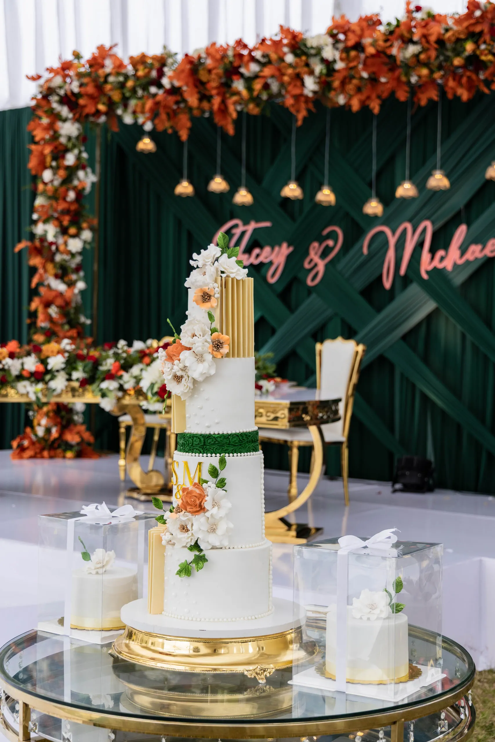 Tiered white and gold cake in front of a floral backdrop