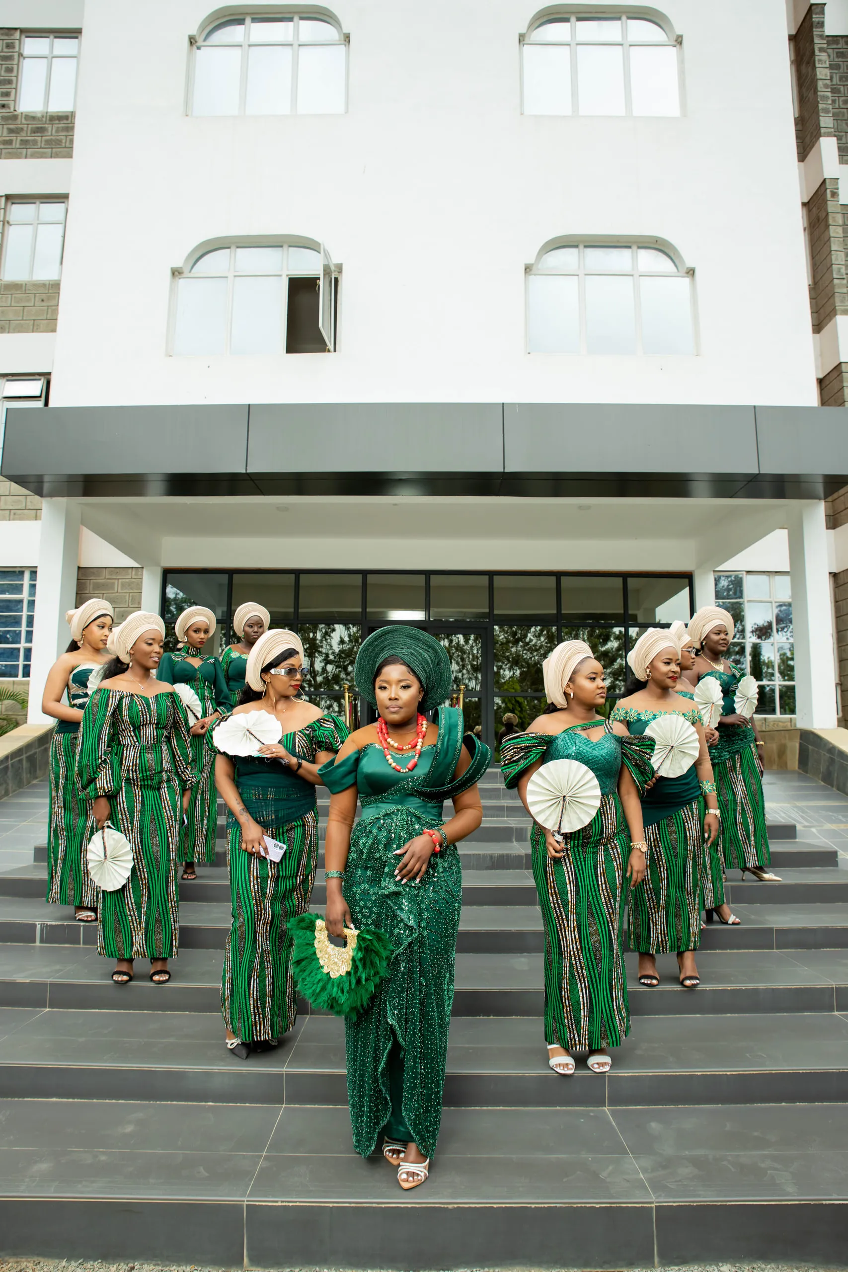 Bridesmaids in green with head wraps and fans on the steps