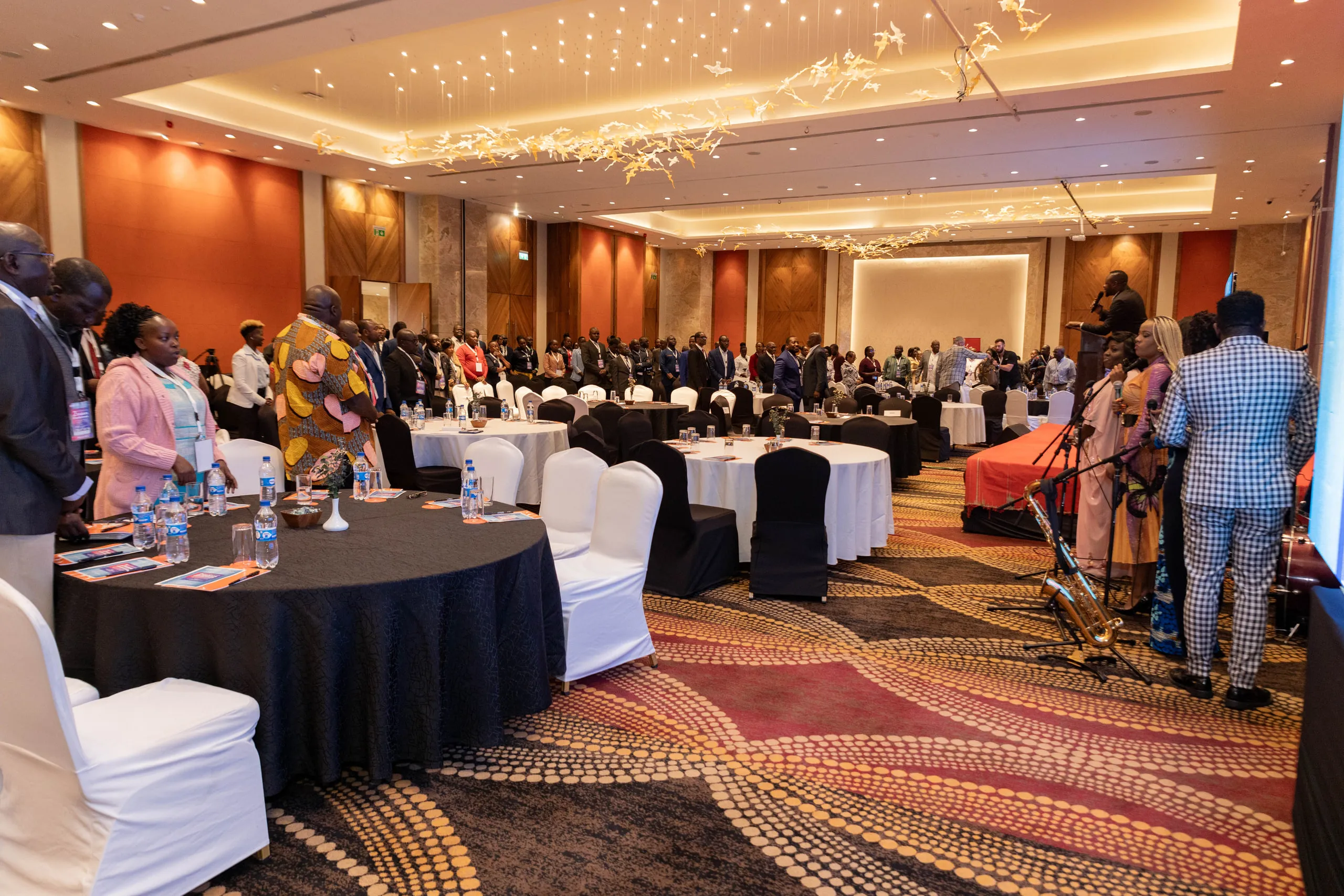 Conference hall with guests standing between round tables and a band at the side