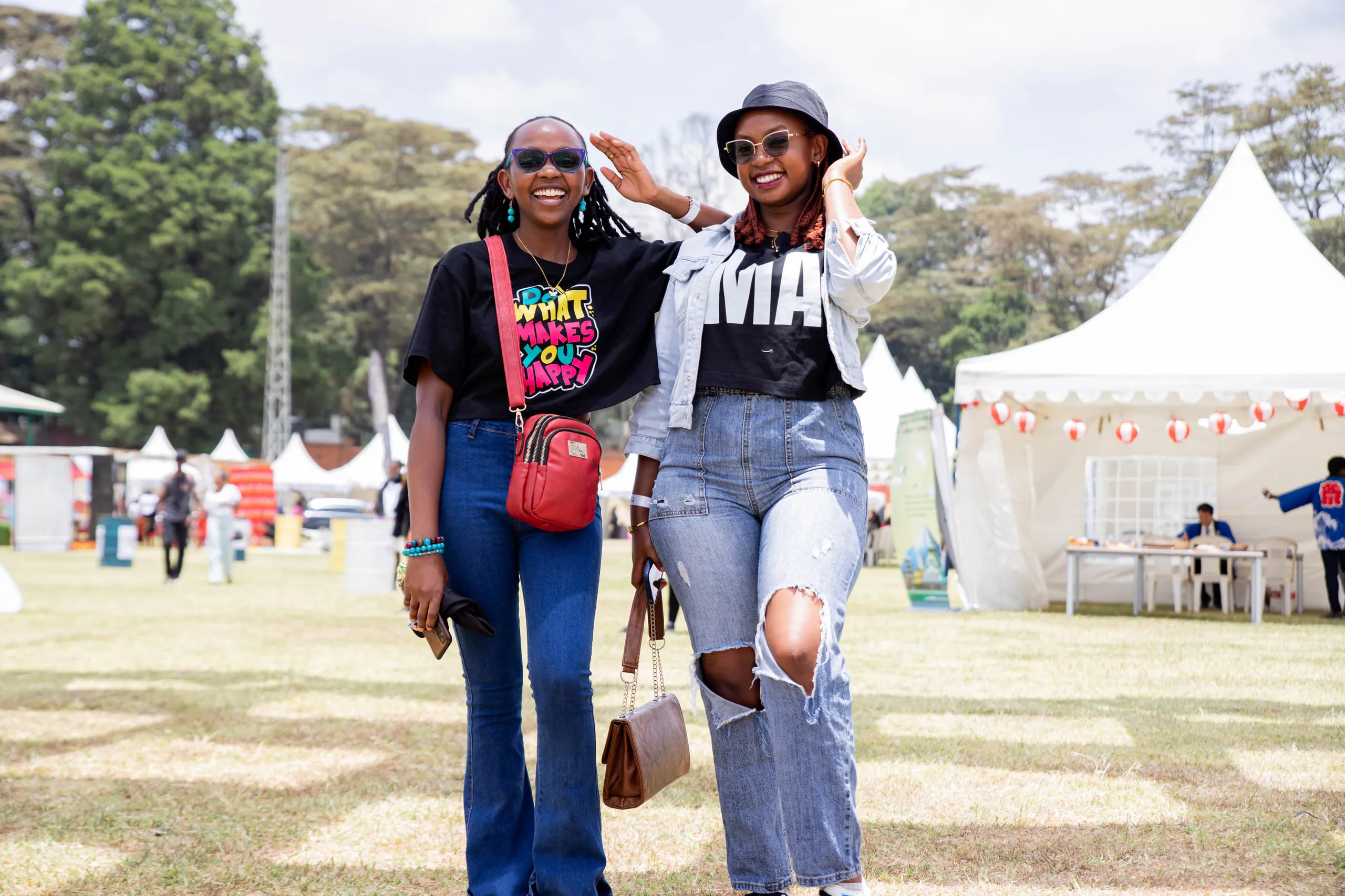 Two women laughing and framing their faces with their hands on a festival lawn