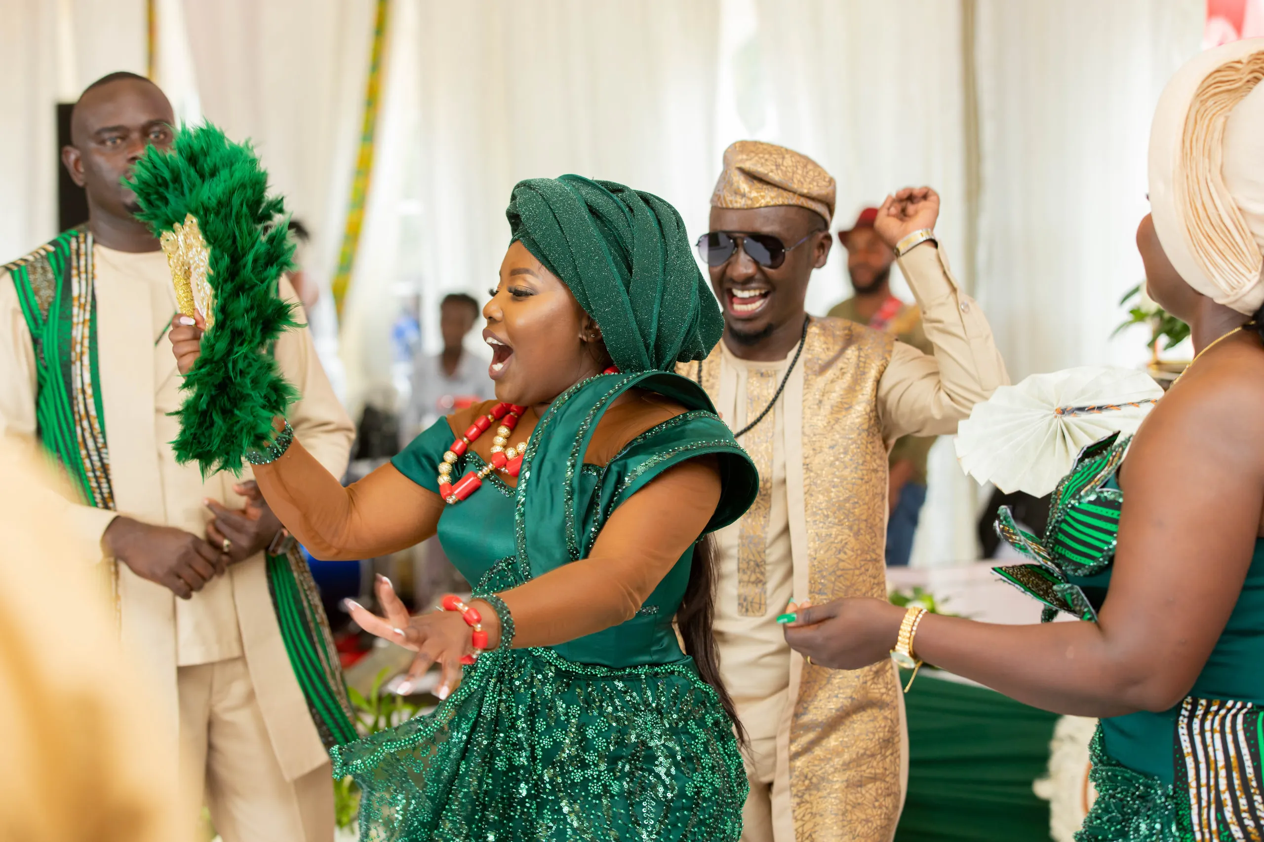 Bride in green dancing with feather fans among the guests