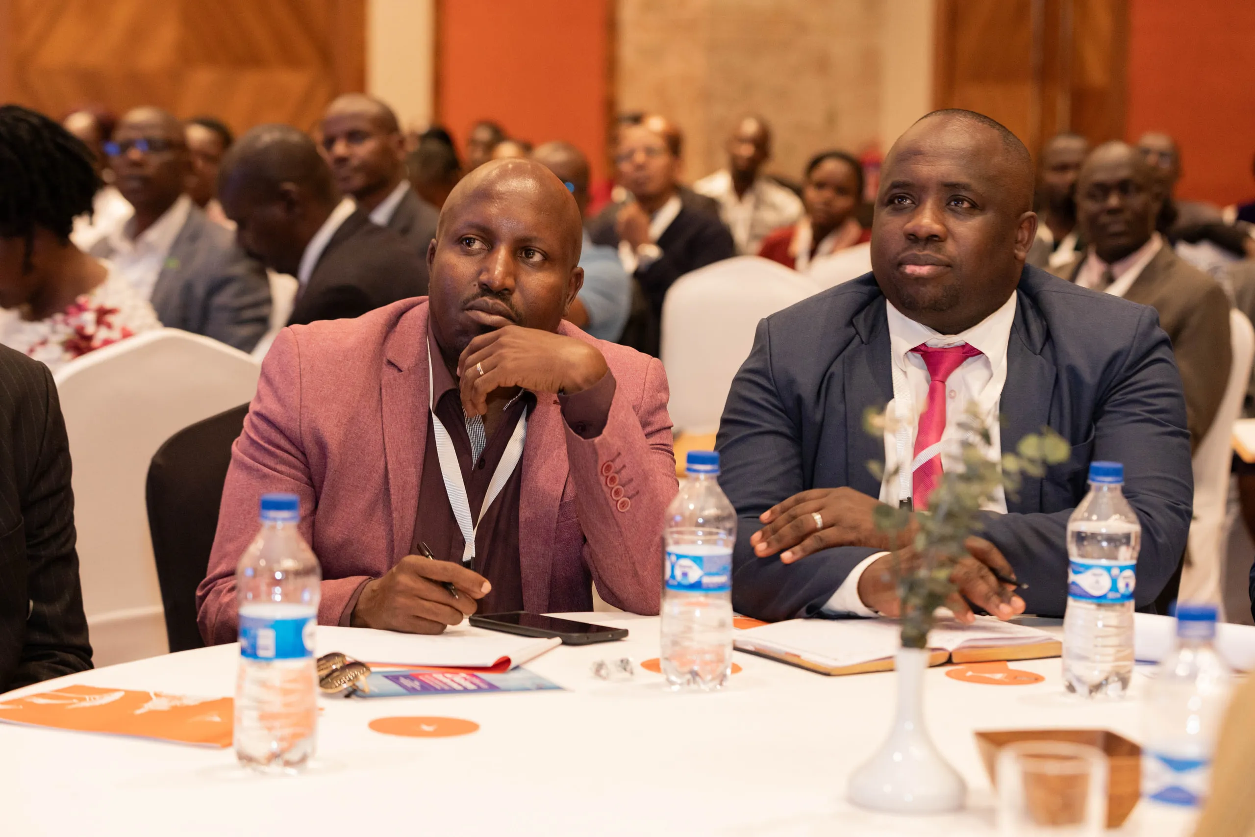 Two men in suits listening intently at a conference table