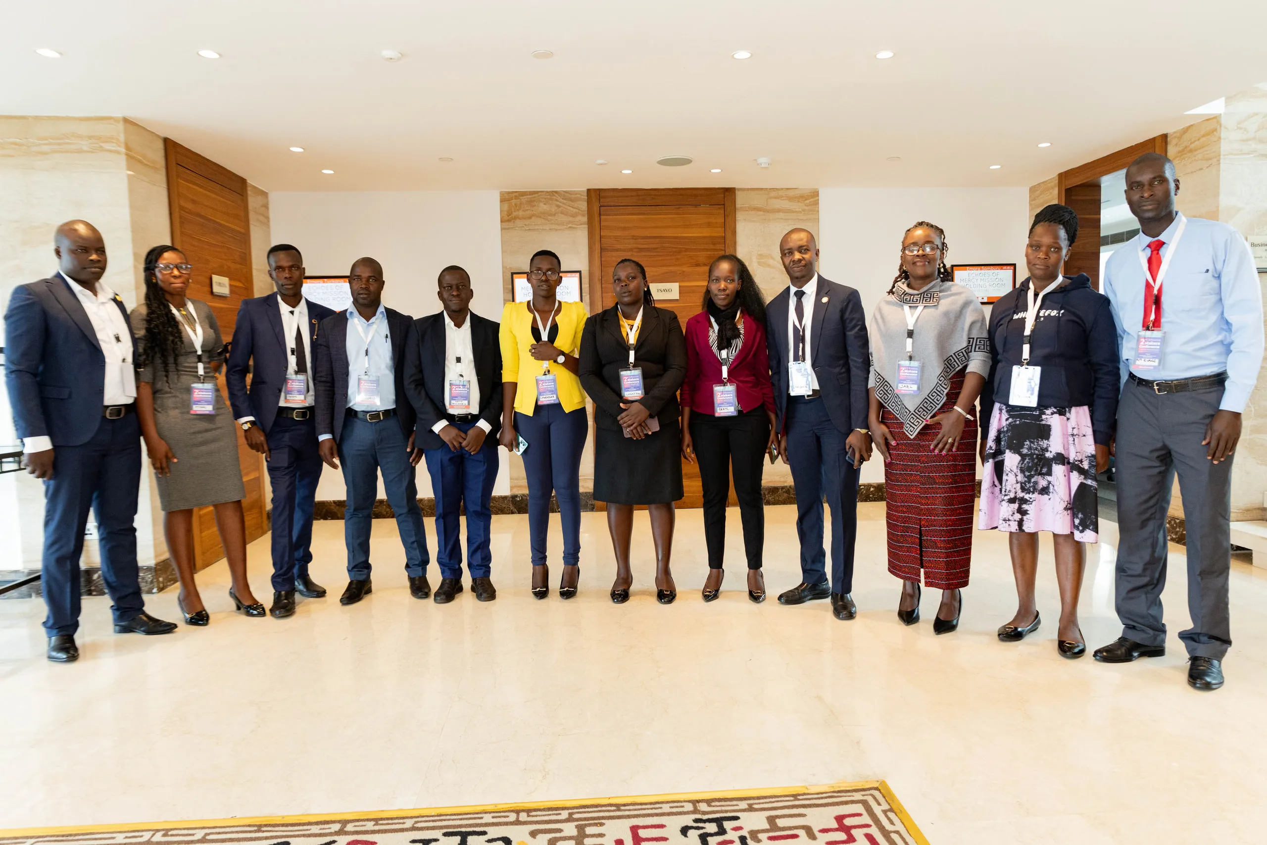 Twelve delegates with name badges lined up in a hotel lobby