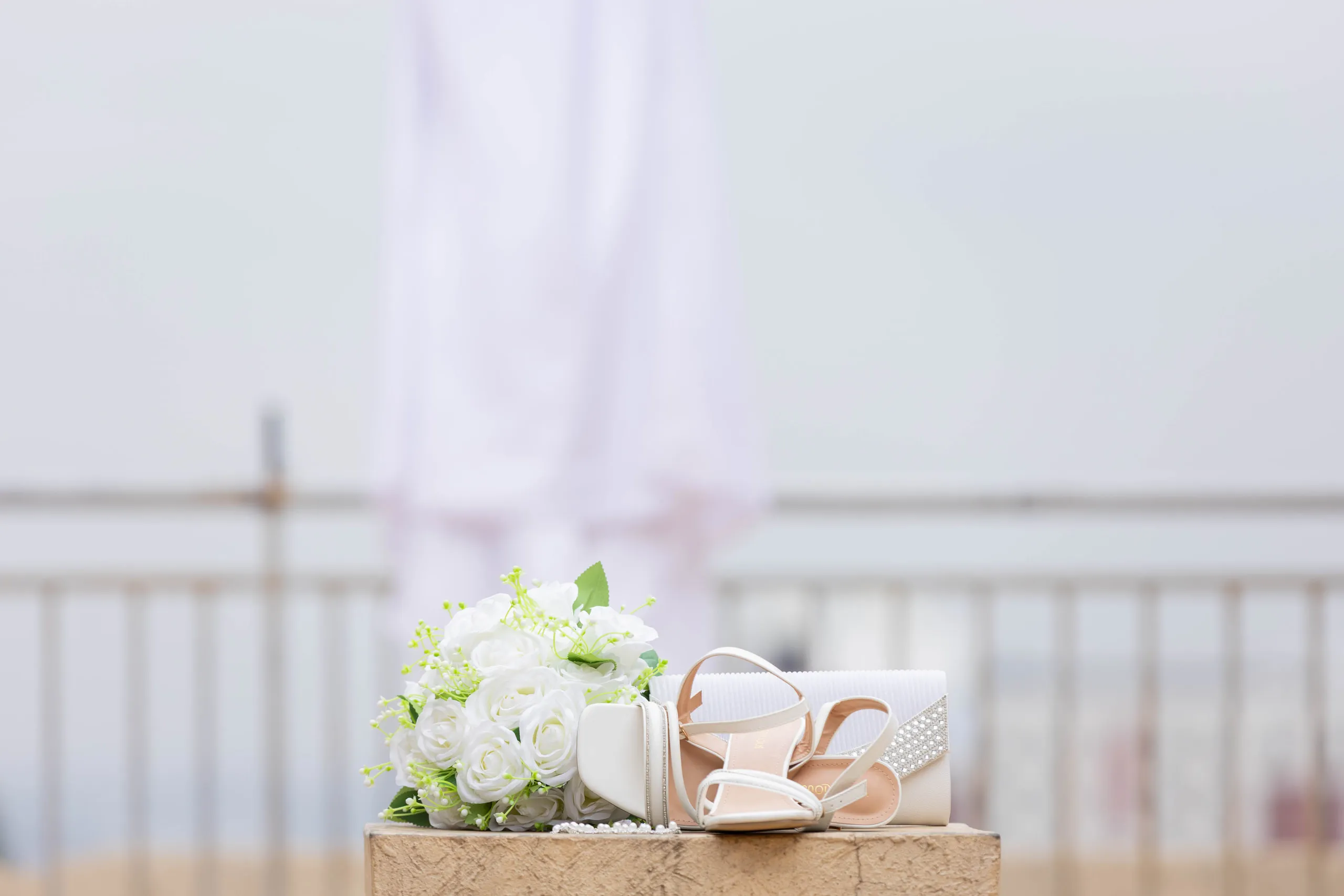 Bouquet, heels and a clutch on a ledge, the gown hanging behind
