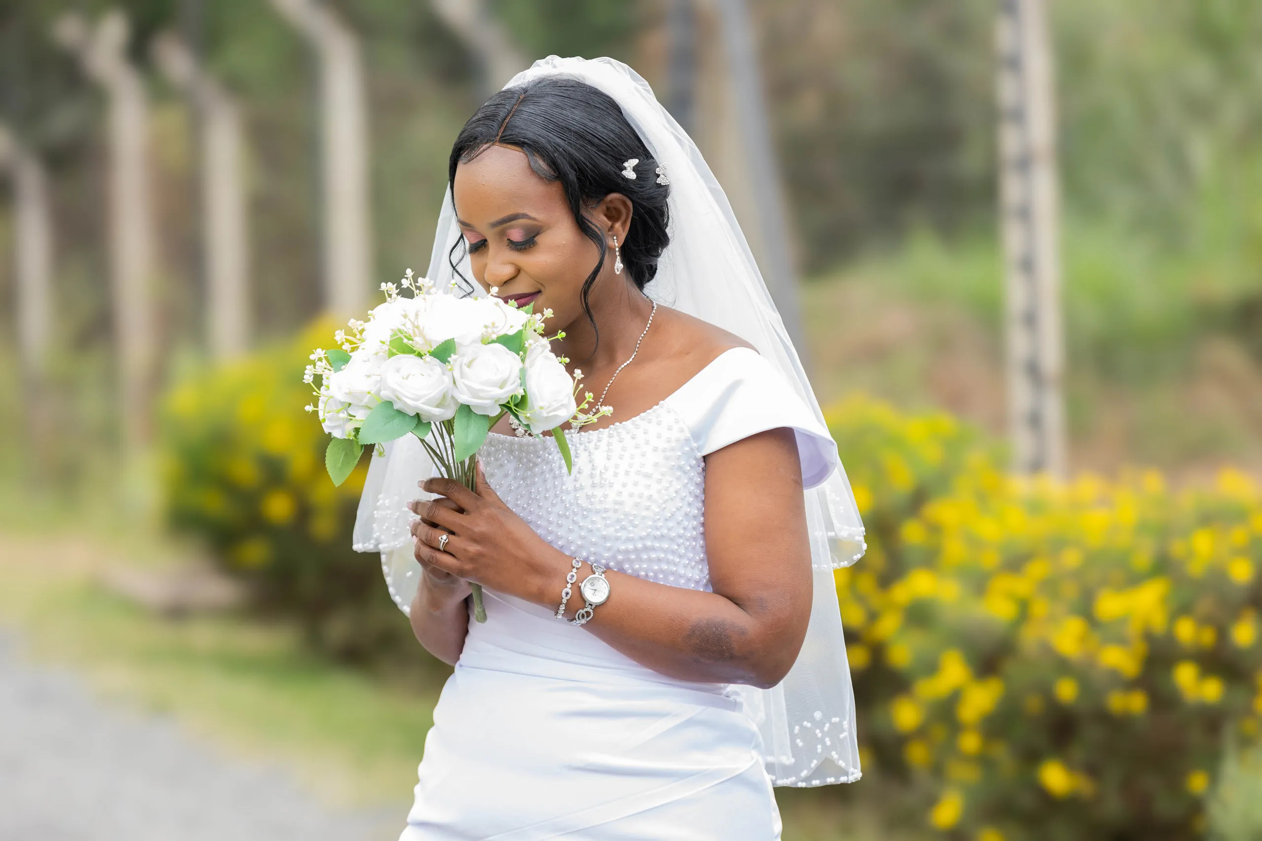 Bride in her veil looking down at her white bouquet