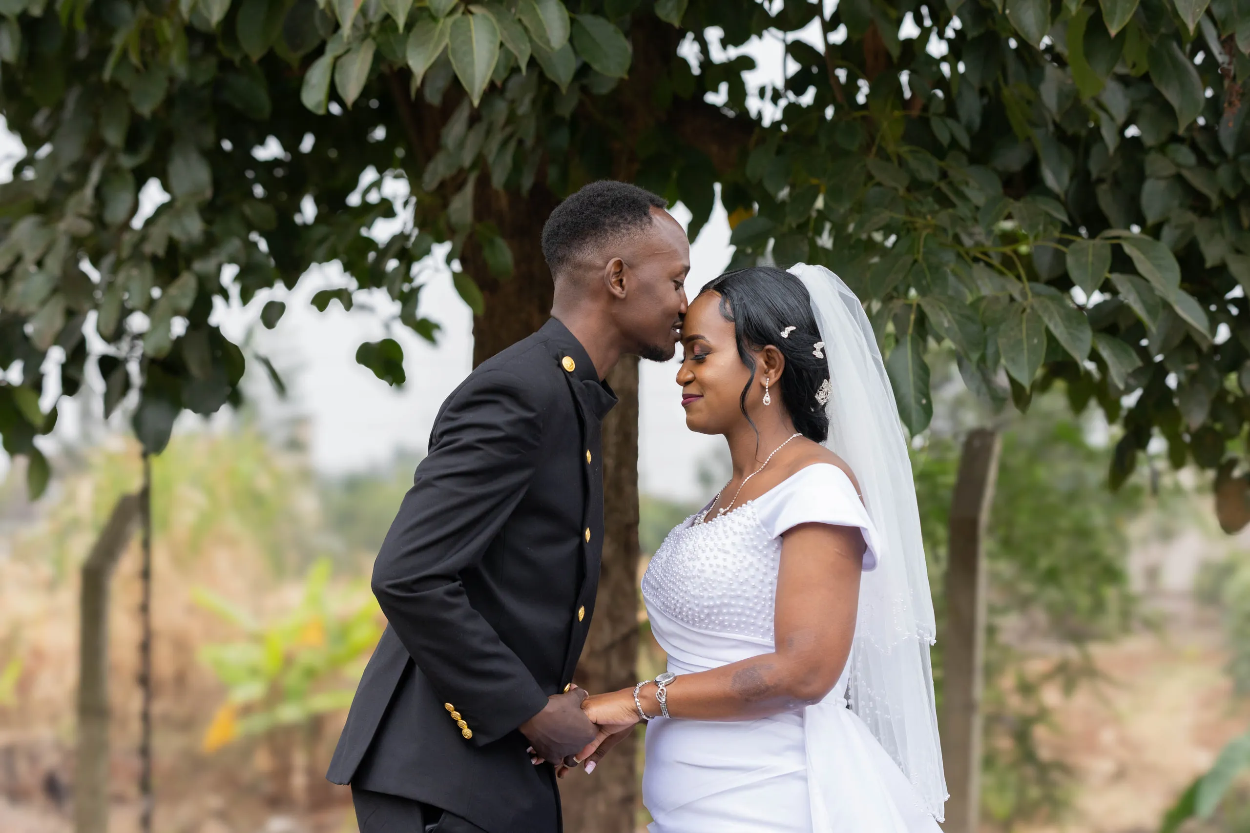 Bride and groom forehead to forehead under a tree
