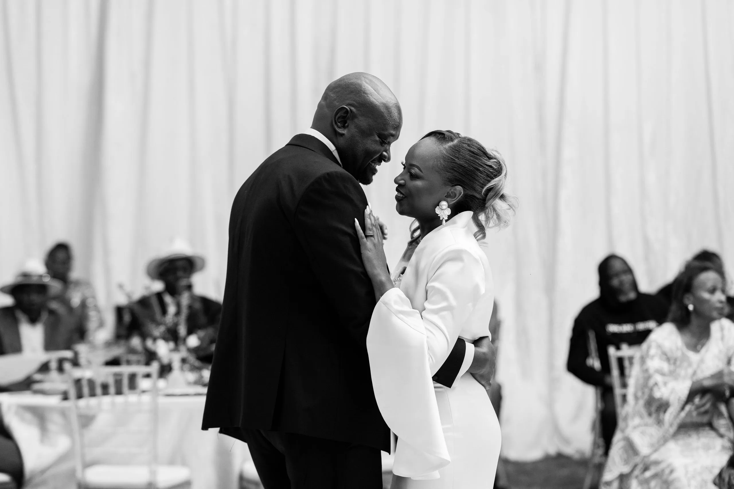 An older couple dancing at the reception, in black and white