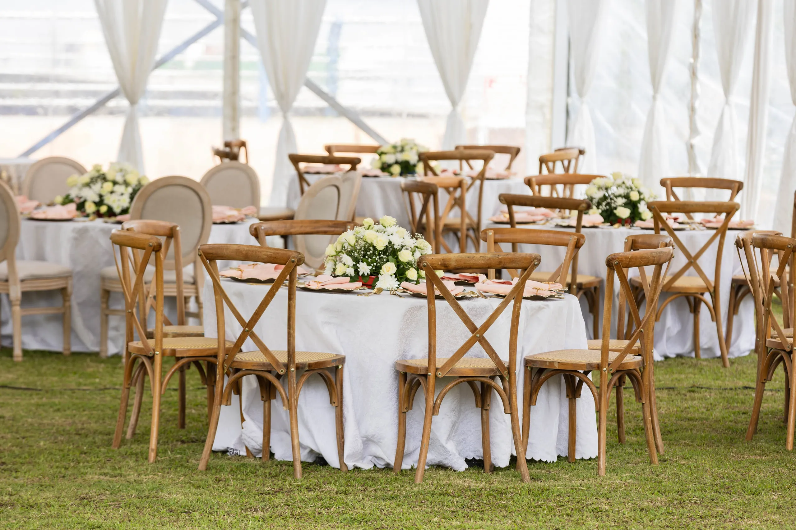Round tables laid out under a white tent on the grass