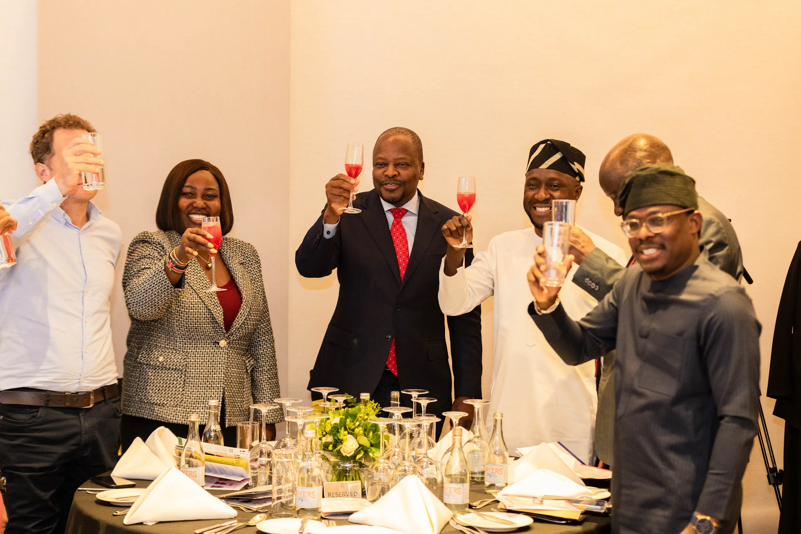 Guests raising glasses in a toast around a dinner table
