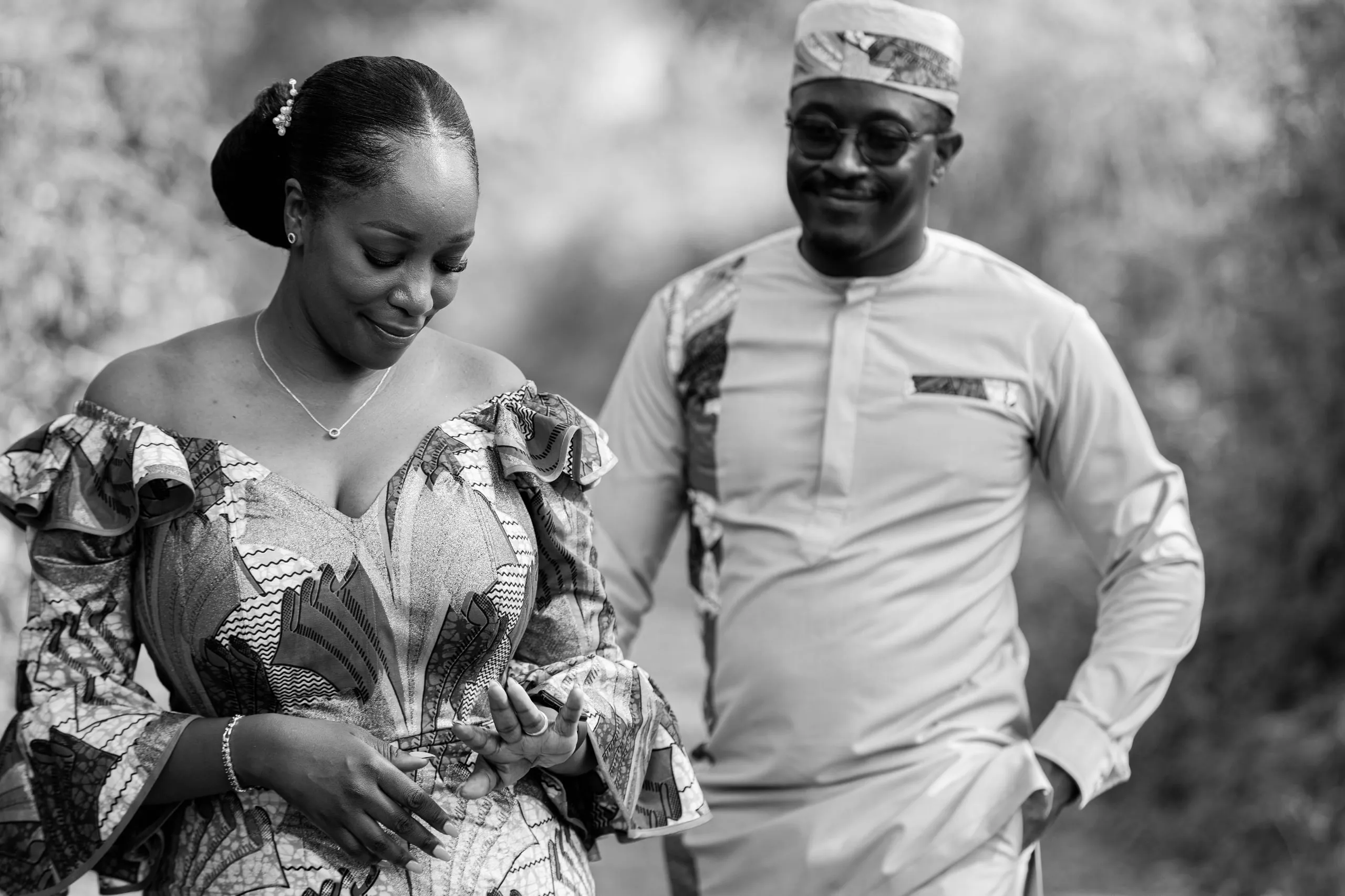 Bride looking down and smiling beside the groom, in black and white