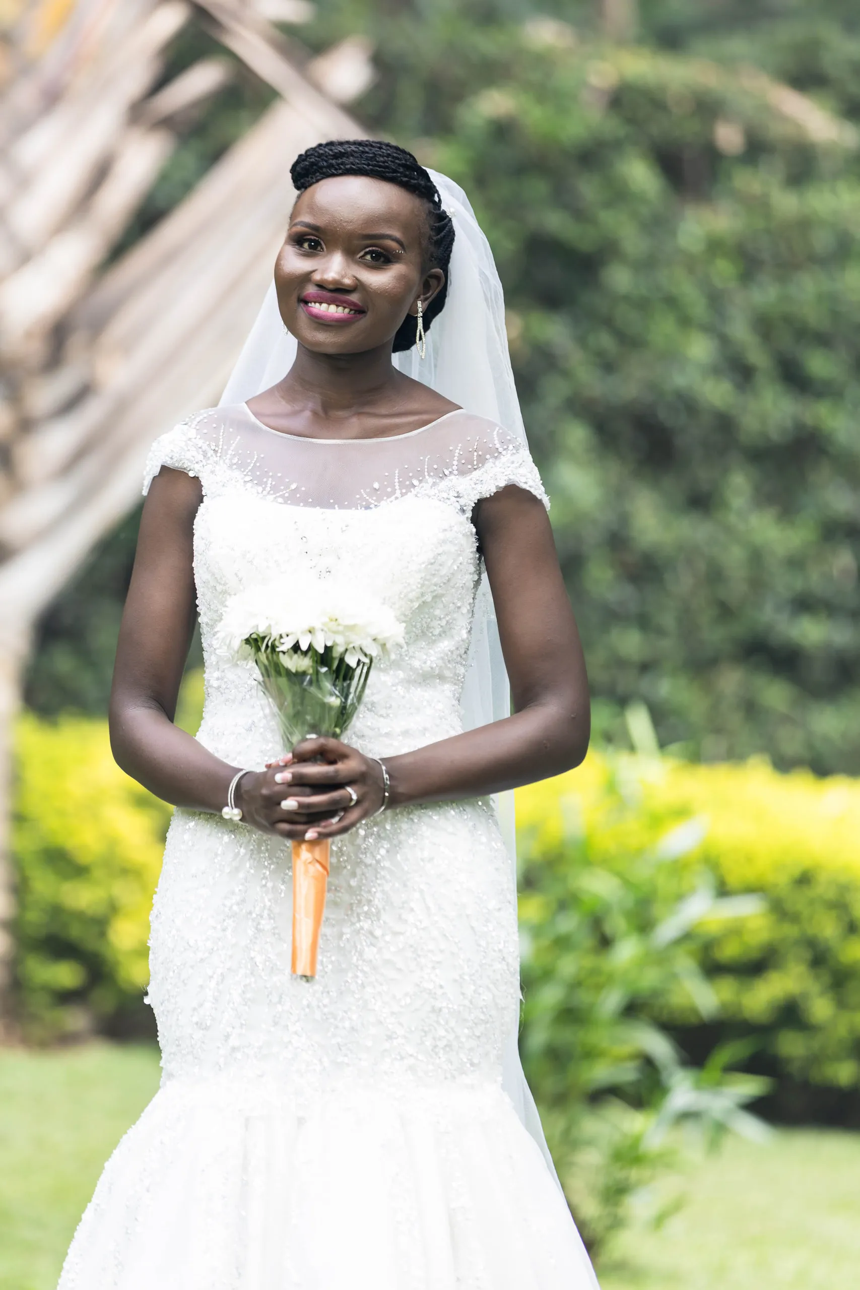 Smiling bride holding white flowers tied with an orange ribbon