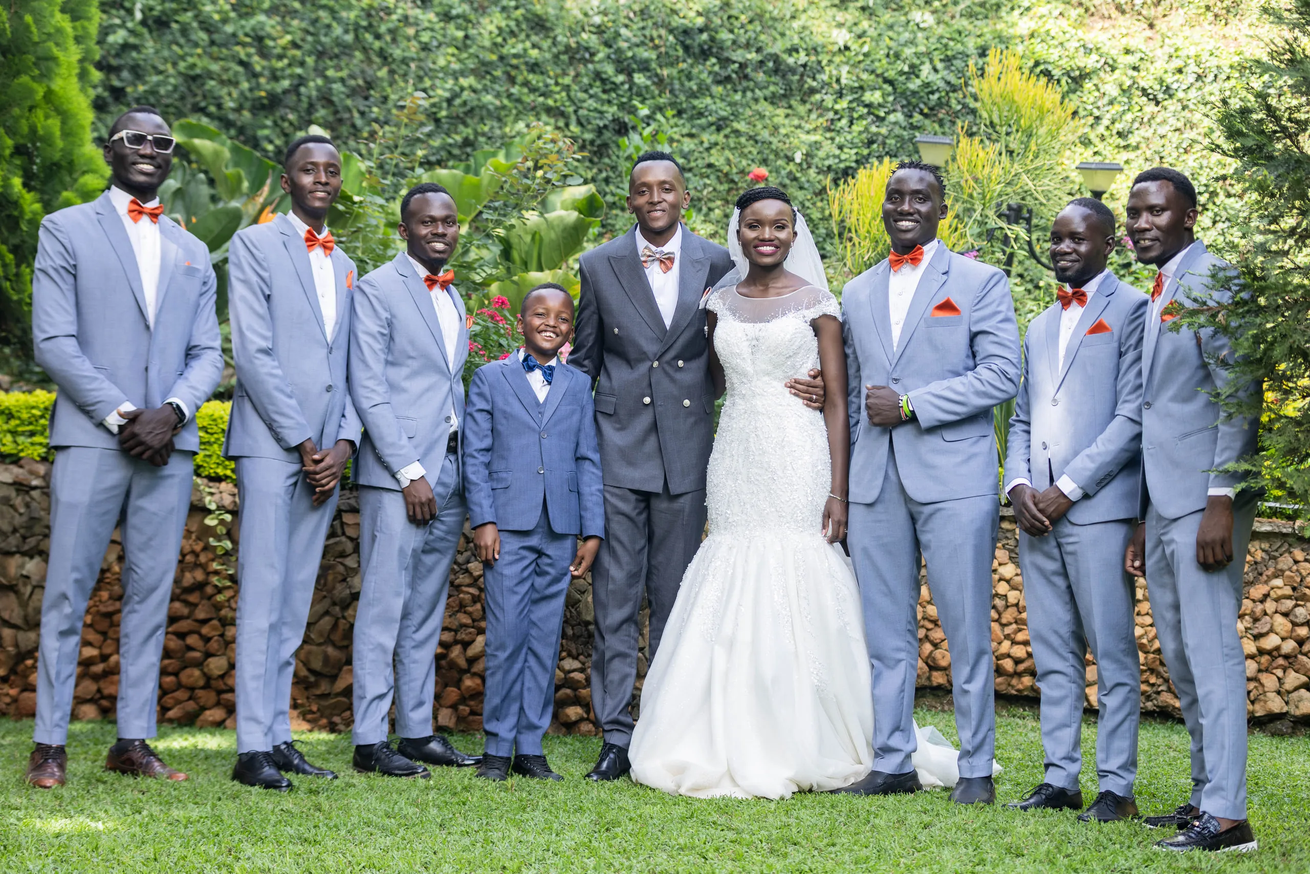 Bride and groom with the groomsmen in light blue suits and a page boy