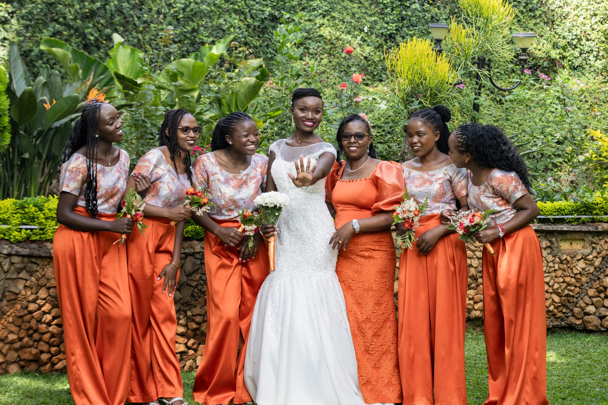 Bride showing off her ring to the bridesmaids in orange