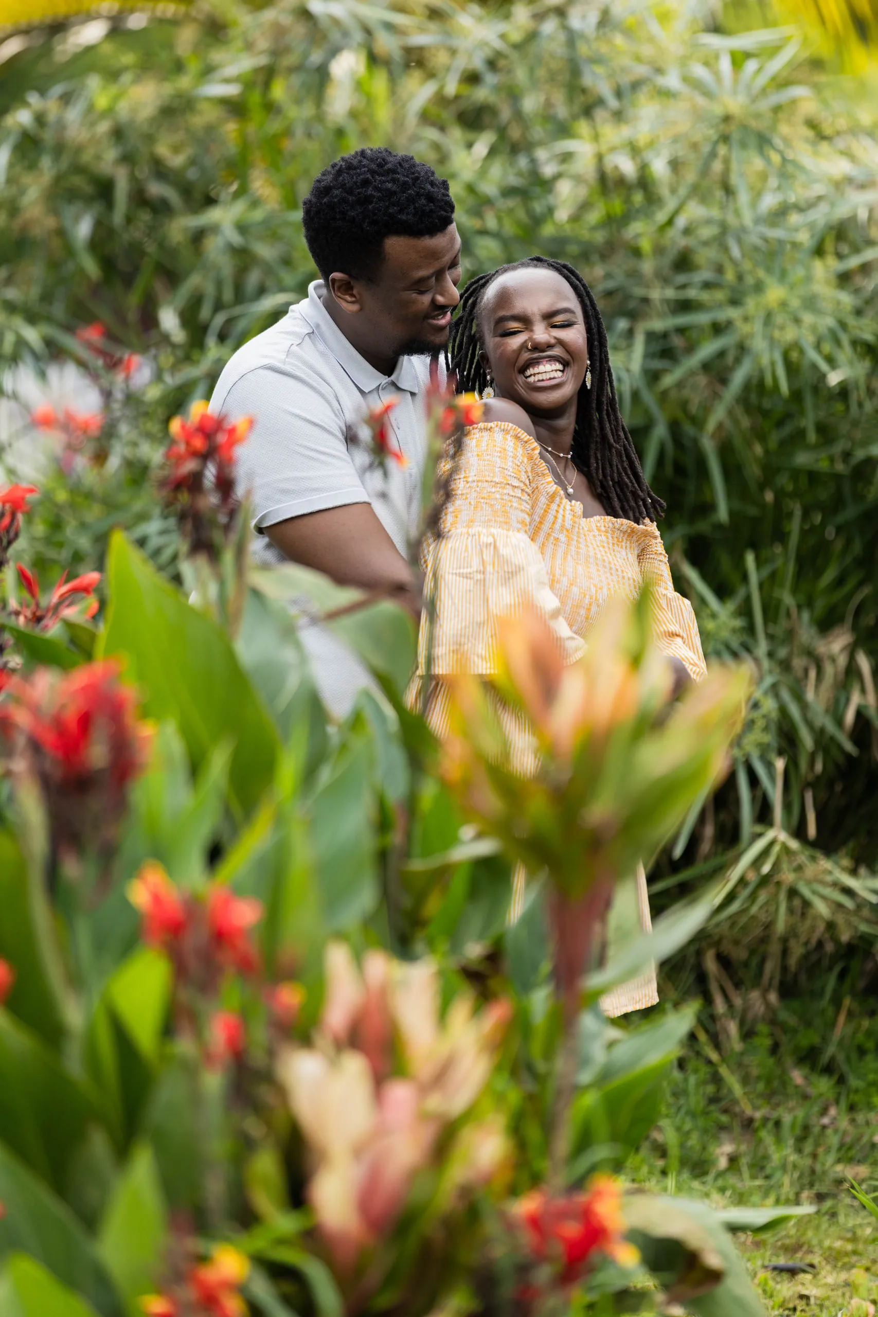 Couple laughing behind red canna flowers