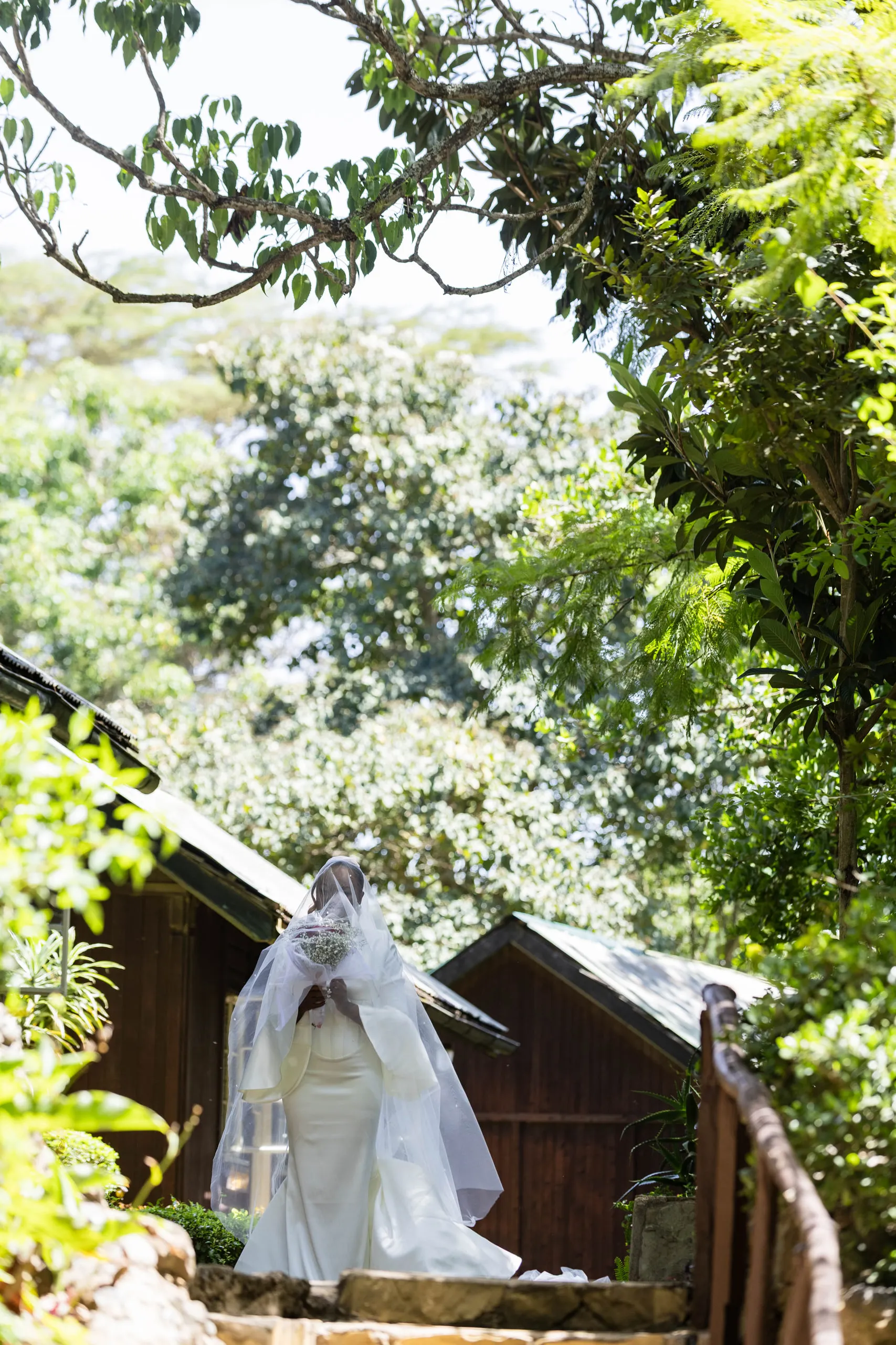Veiled bride coming down the steps between wooden cottages
