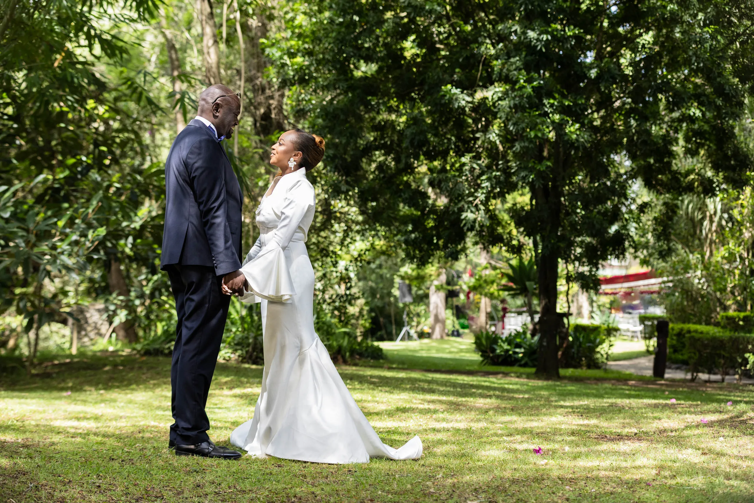 Bride and groom facing each other under tall trees