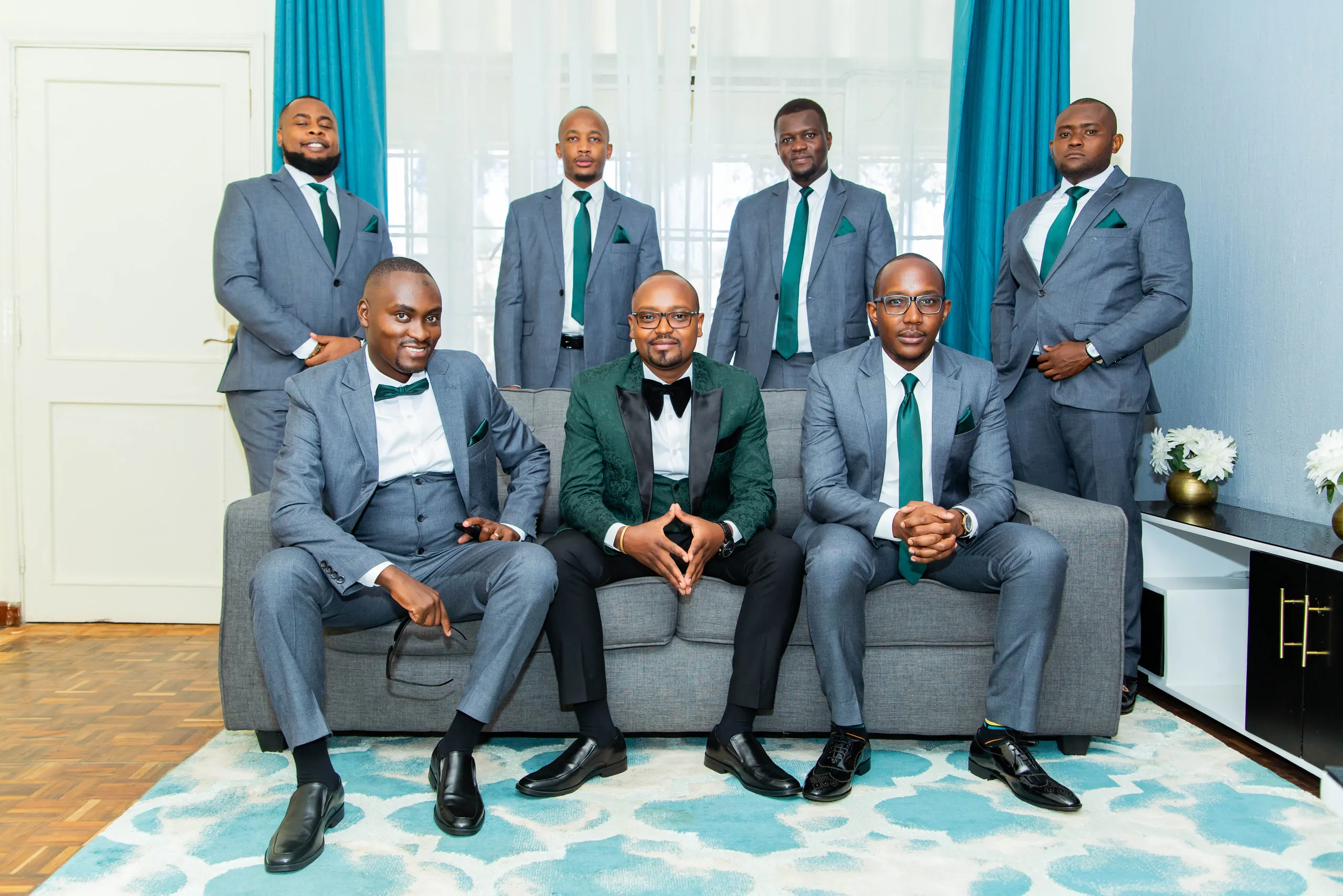 Groom in green velvet with his groomsmen in grey on a sofa