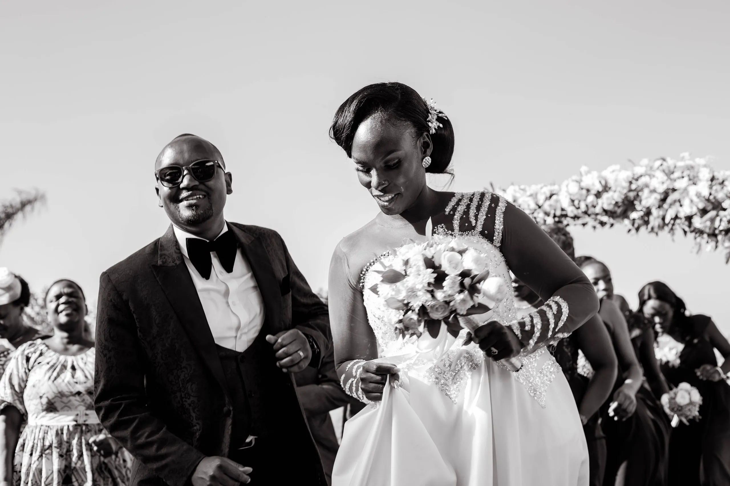 Bride and groom walking out among their guests, in black and white