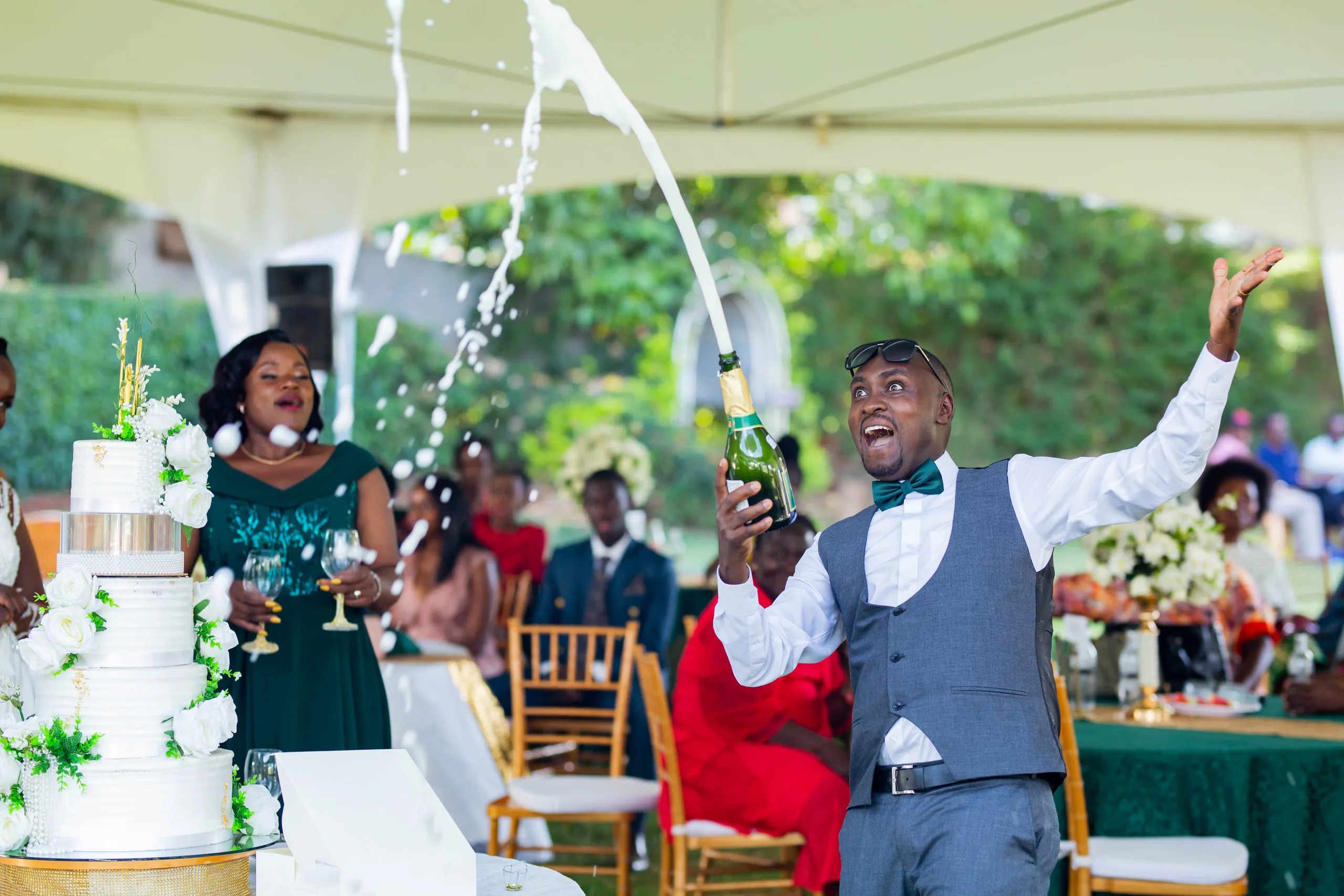 A guest spraying champagne beside the wedding cake