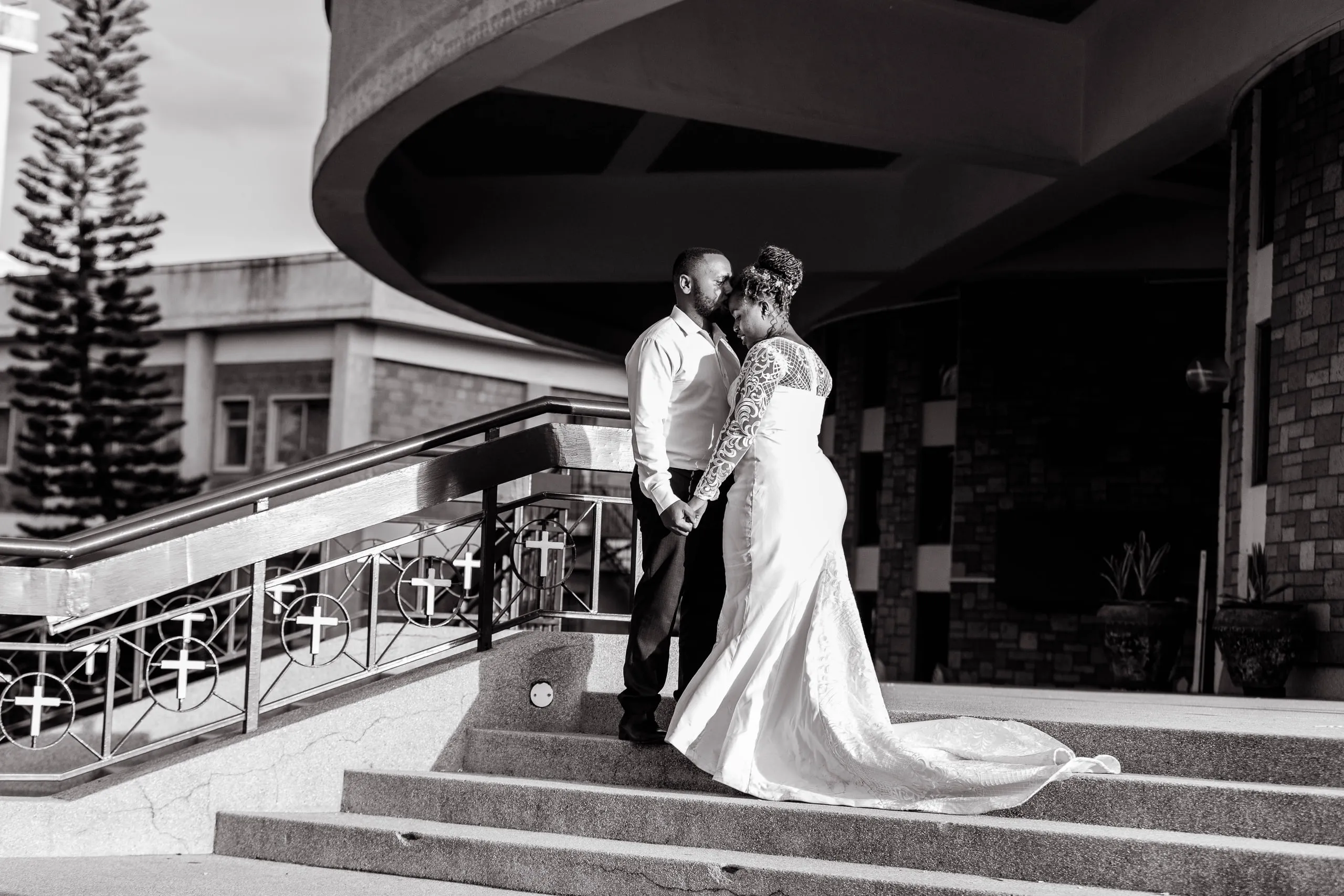 Bride and groom on curved stone steps, in black and white
