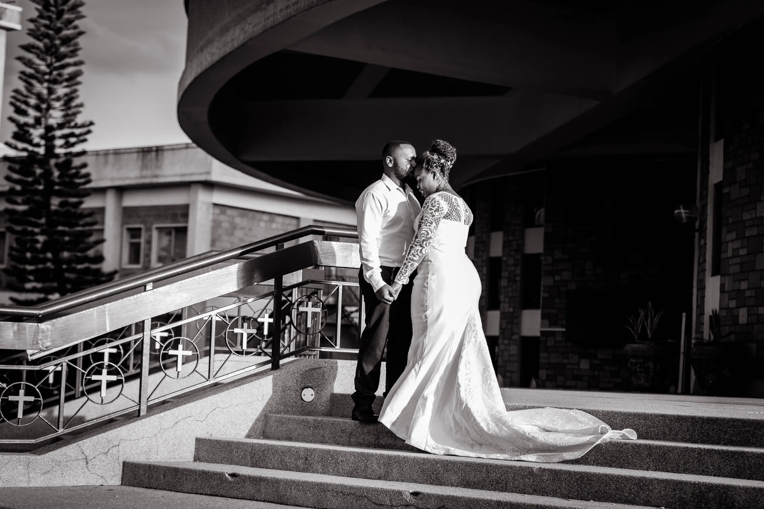 Bride and groom on the steps of a round building, in black and white