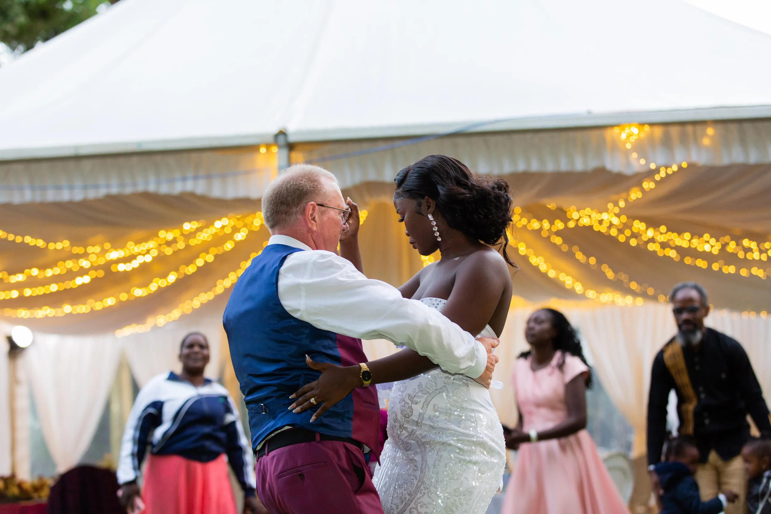 Bride and groom dancing under fairy lights in a tent