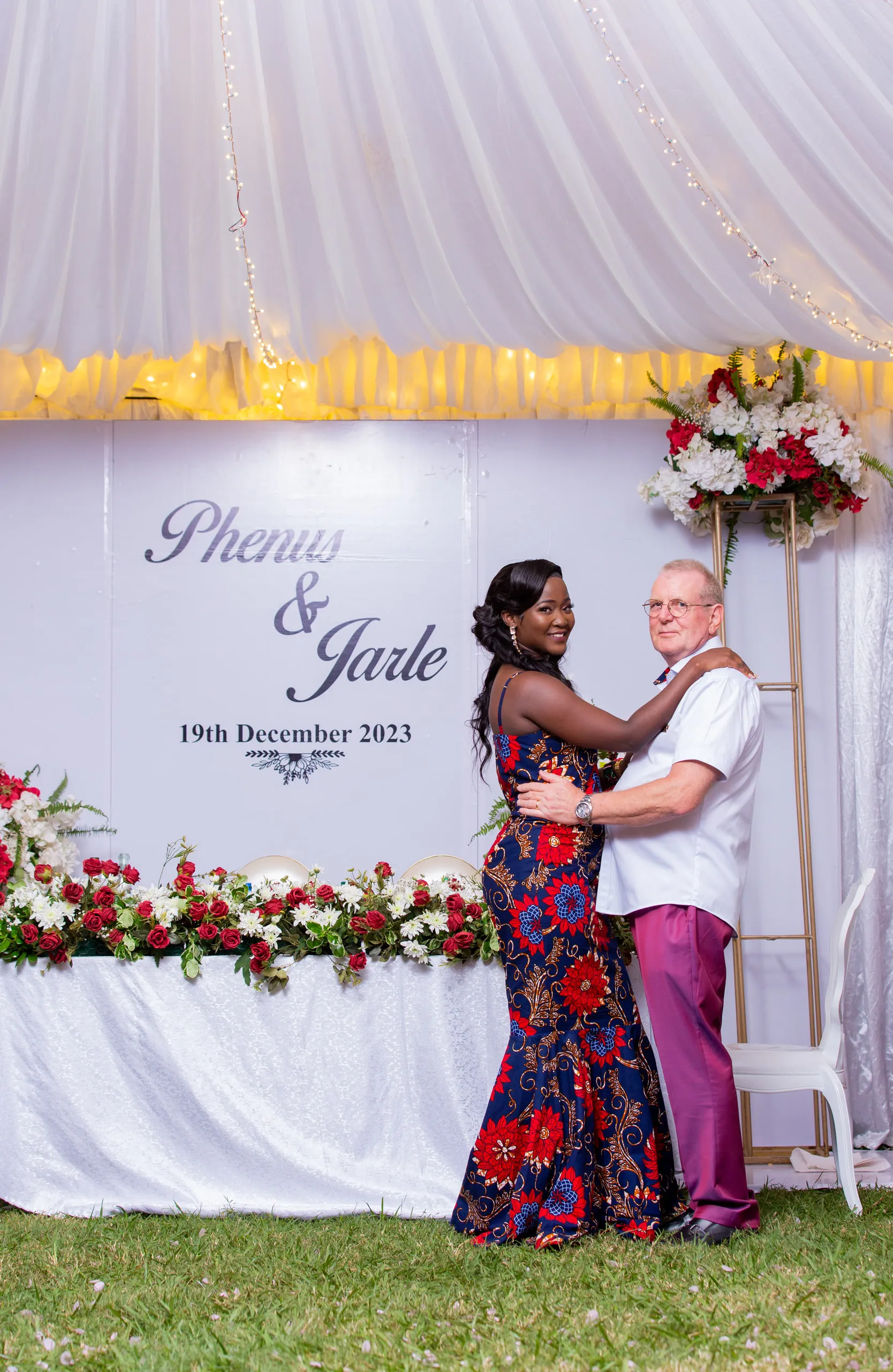 Bride and groom in their evening outfits in front of the head table