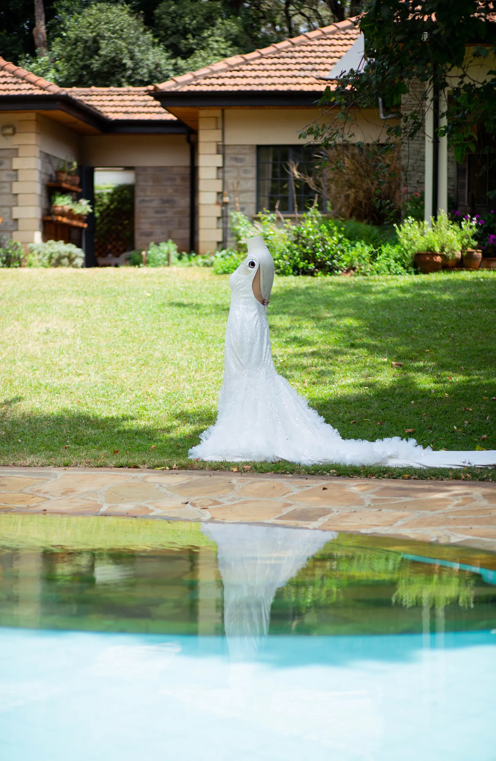 Wedding gown on a stand, reflected in a swimming pool